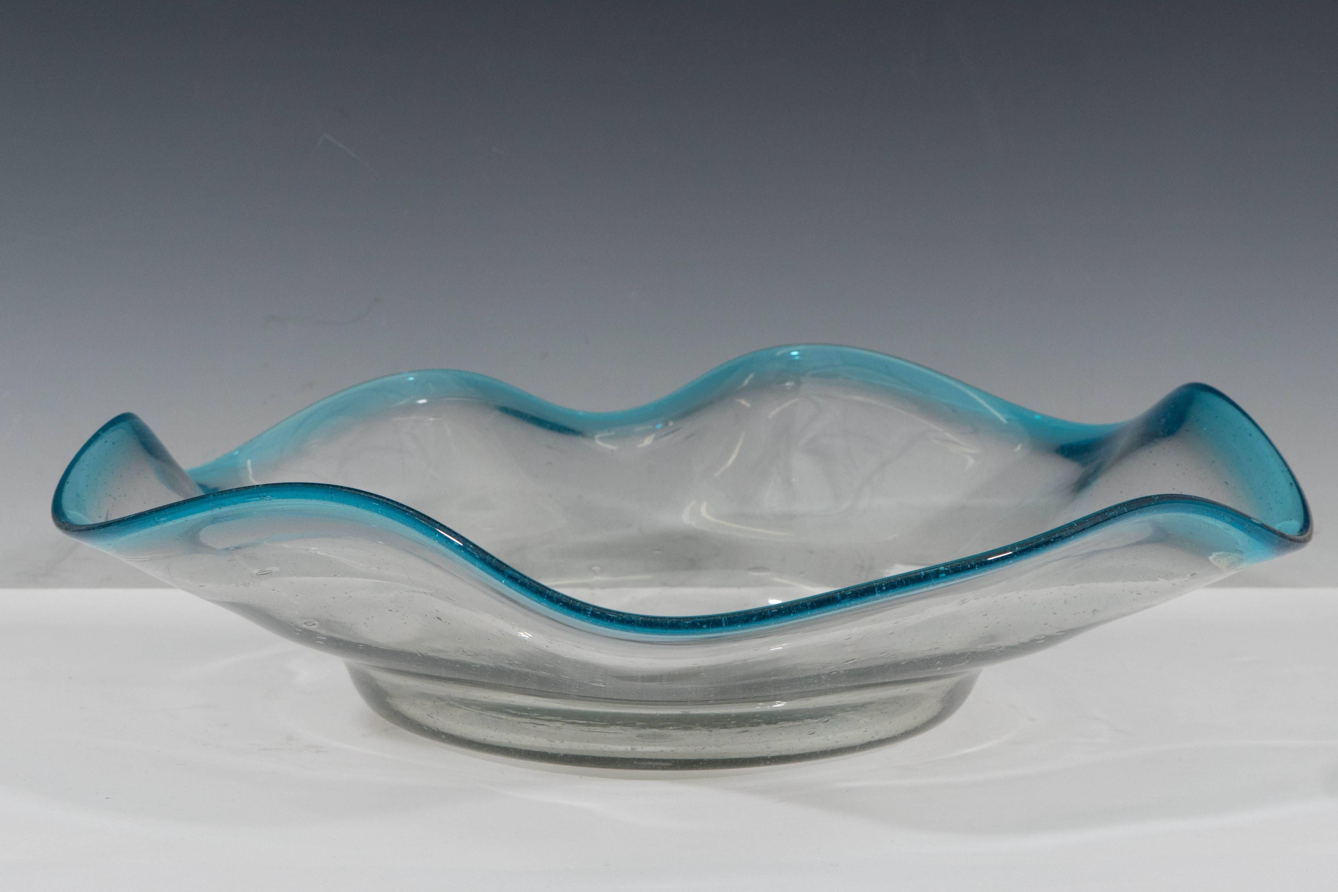 A vintage decorative bowl, in handblown Murano glass, produced circa 1950s in Italy, with scalloped, blue tinged rim, raised on circular base. This glass piece is in overall very good condition, consistent with age and use; inclusion of naturally