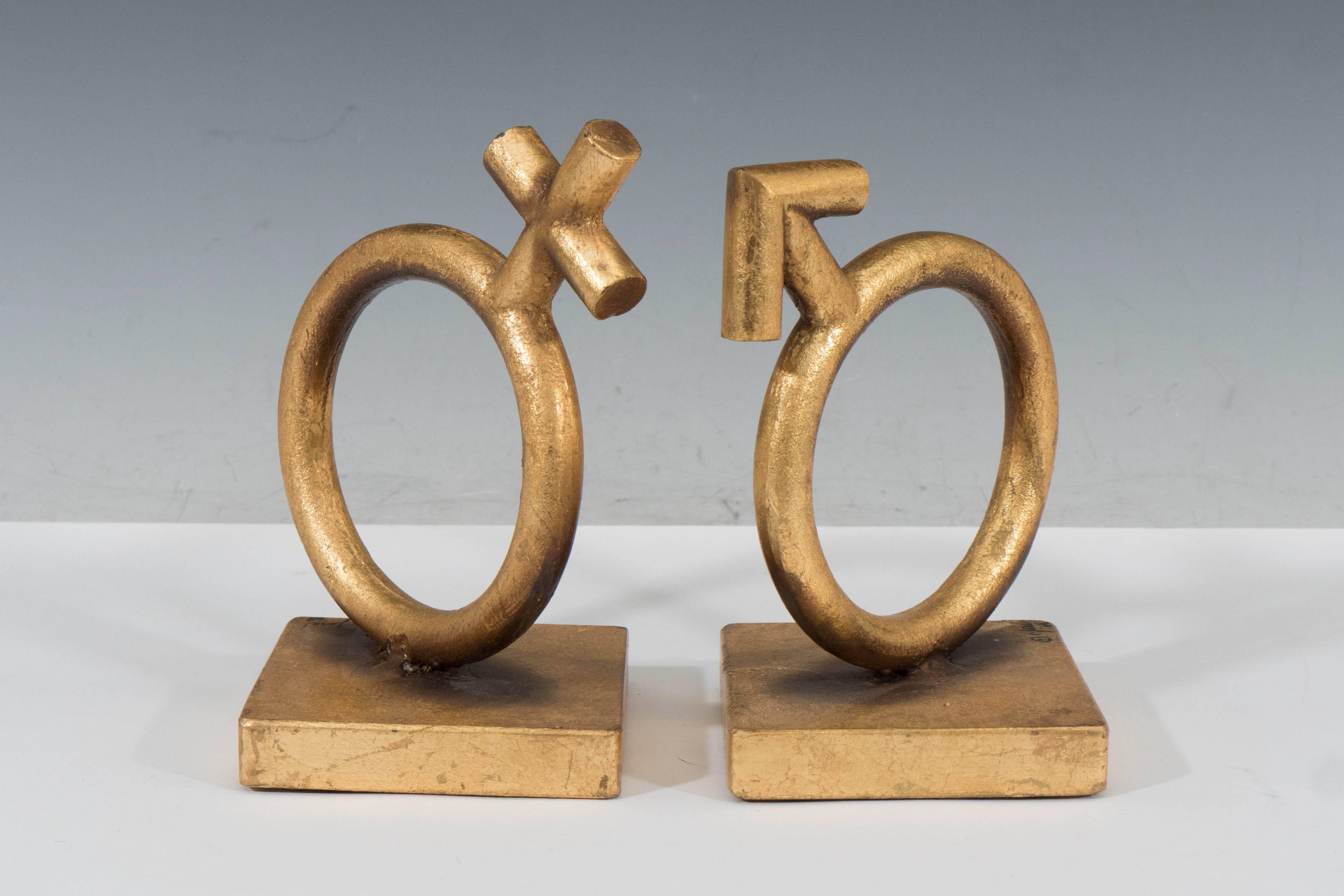 A pair of vintage Curtis Jere sculptural bookends, entitled 'The Sexes', either depicting the male and female gender symbols on square bases, in gold gilt metal. Markings include signature [© C. Jere/1968], signed to the corner bases of both pieces.