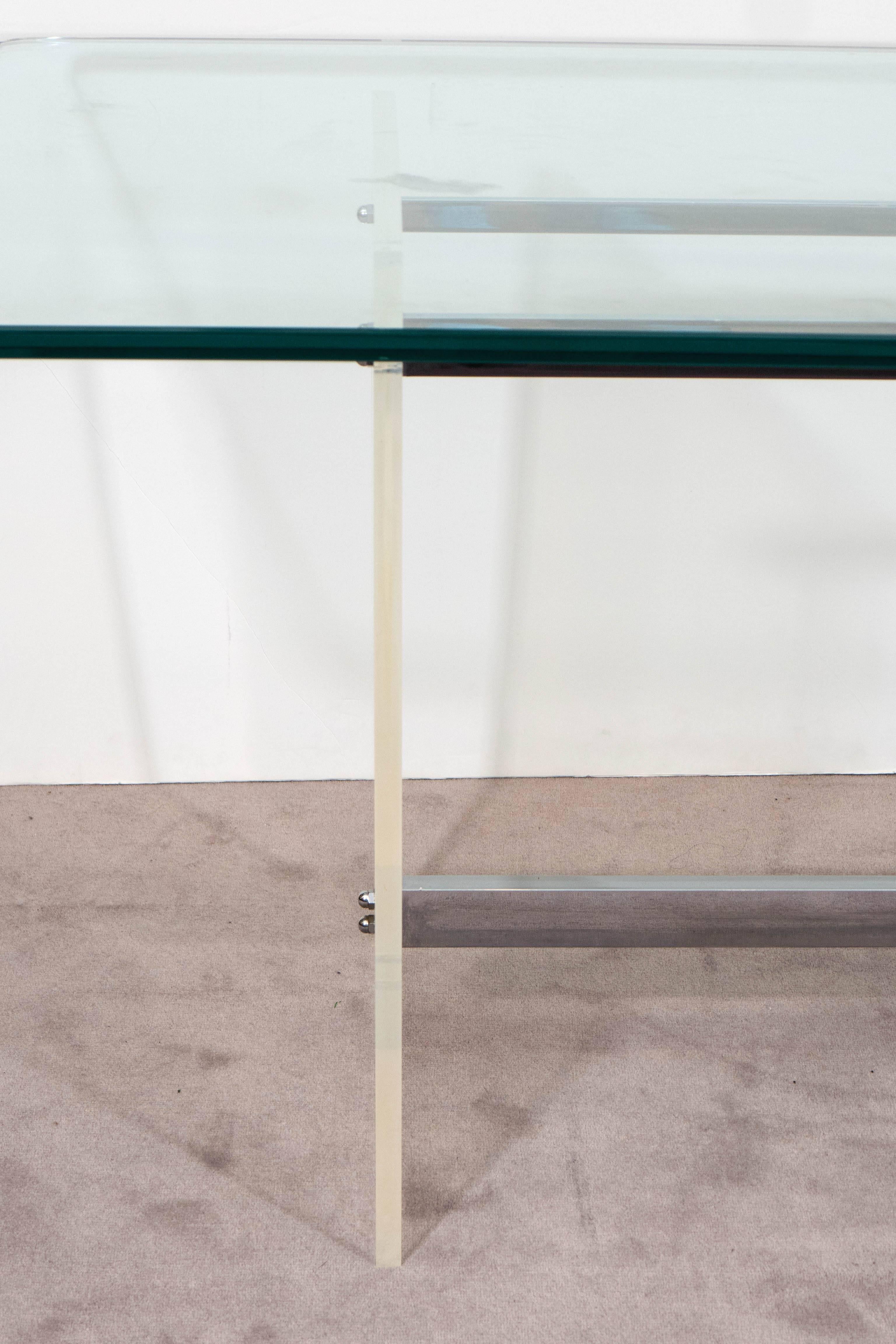 A console table, with glass top over highly modern base, with Lucite supports and three chrome spreaders. Overall good condition, consistent with age and use, with slight wear, including minor scratches to the Lucite.