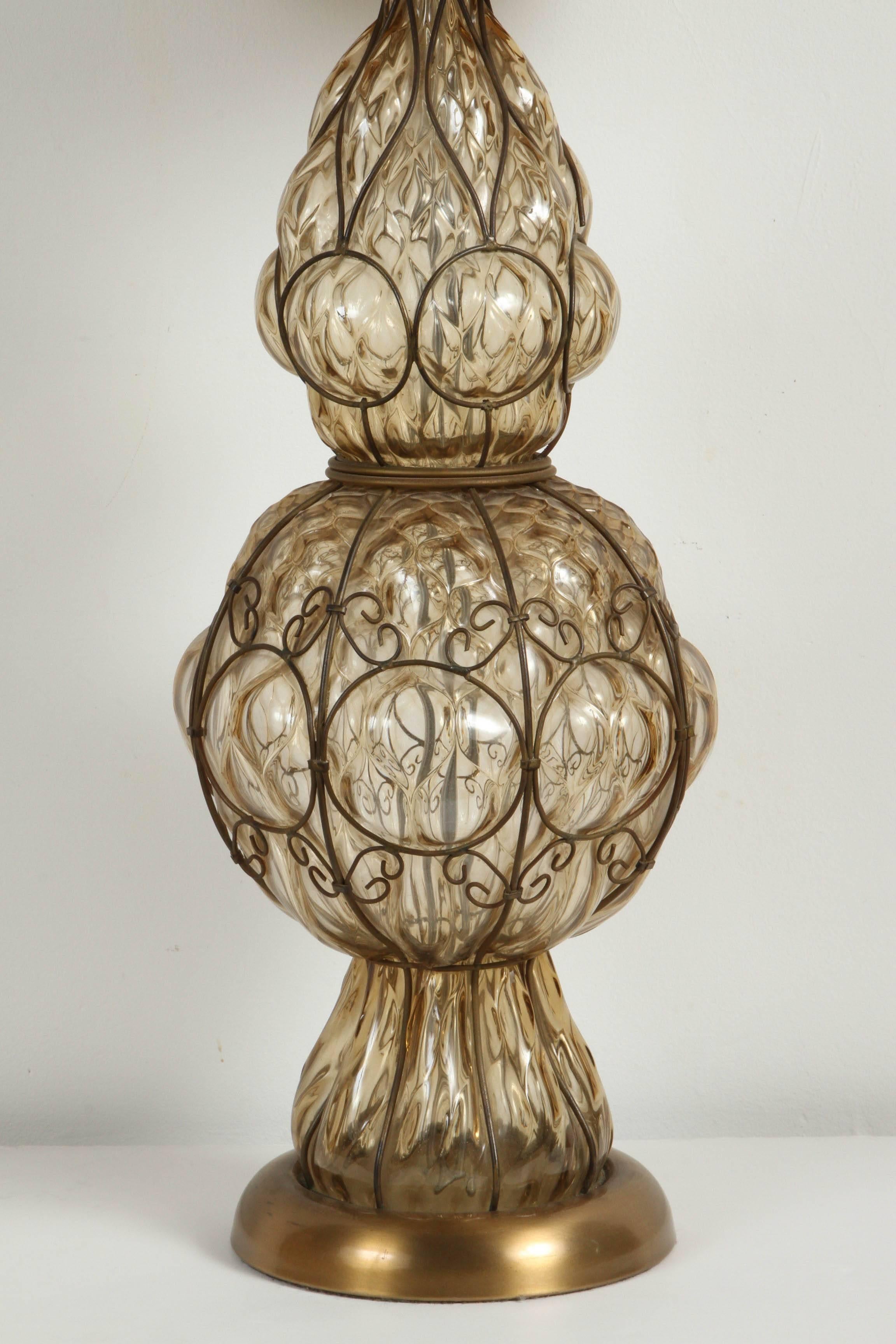 Lampe de table en verre ambré à bulles d'air de Murano, d'origine italienne, du milieu du siècle dernier, signée Marbro.
Verre soufflé à la main de style vénitien avec design de cage câblée en métal.
Mesures : La base a un diamètre de 9