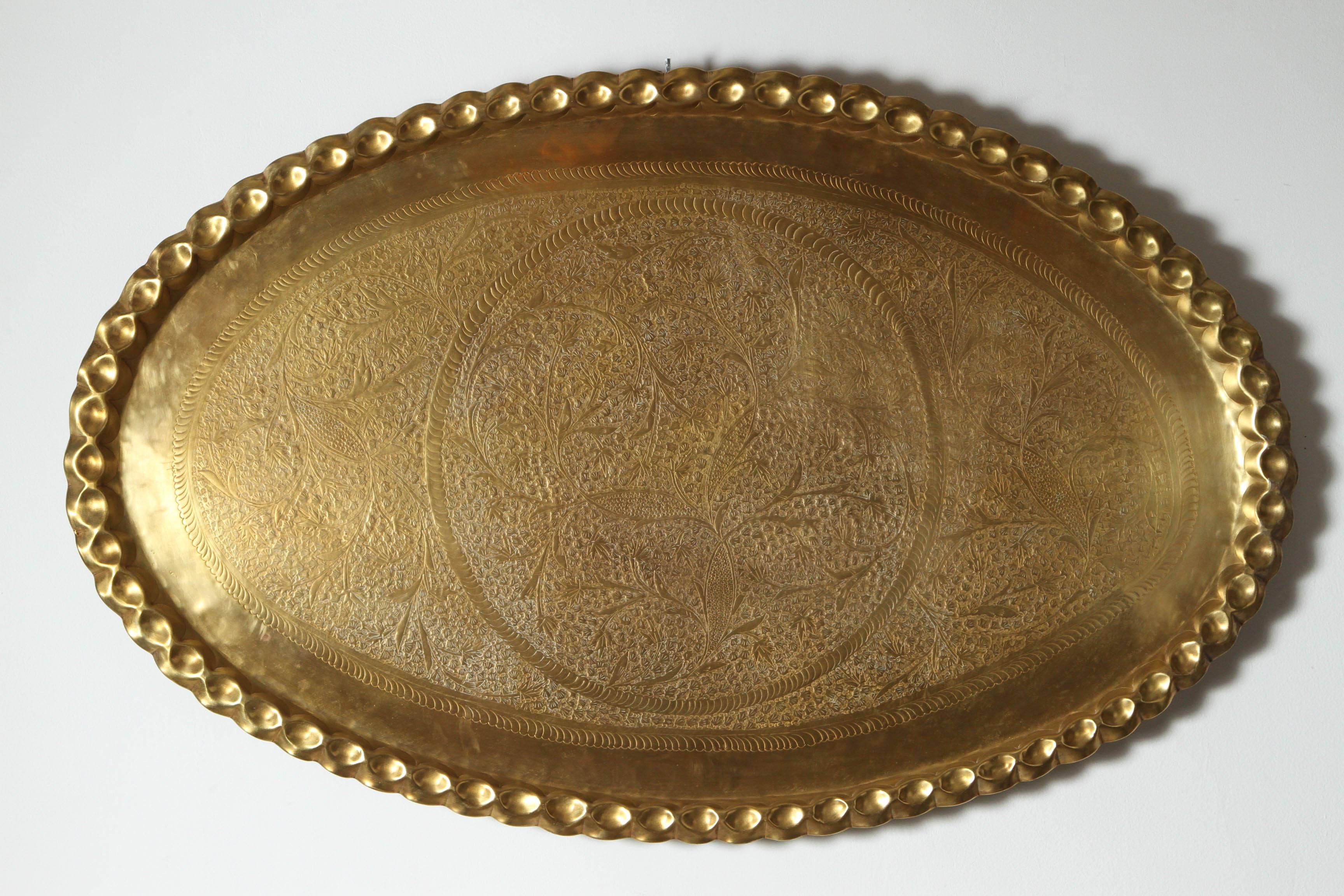 Mid century Modern stylish large oval hand-etched, hammered and embossed, chiseled Moroccan polished brass tray with pie crest edges.
Very finely hammered in floral Moorish designs, use it on a large ottoman, indoor or outdoor.
Has a hook in the