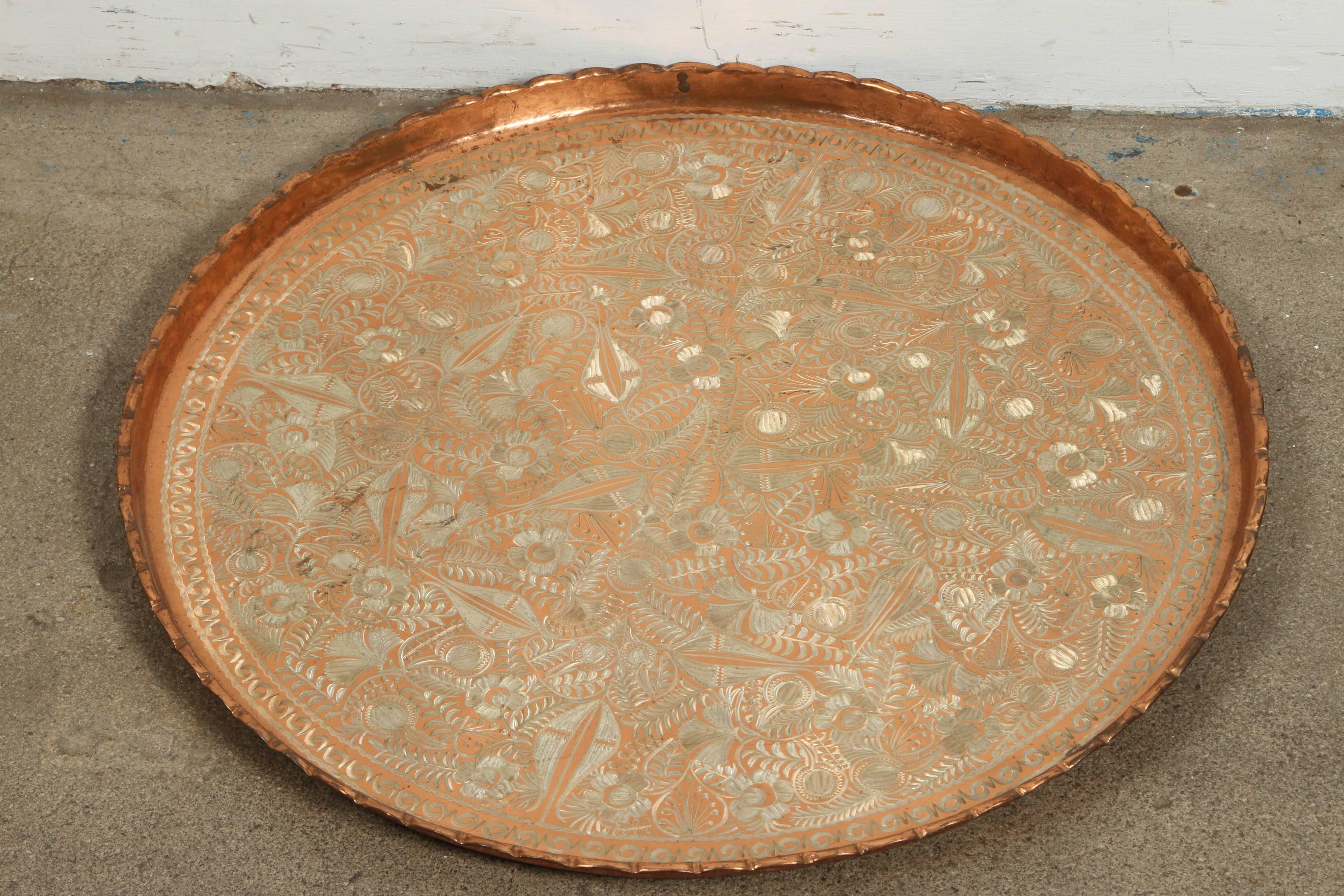 Large Turkish hanging copper platter.
Nicely and heavily hand-hammered Middle Eastern tray and etched with floral designs in silver color.
Hang it on the wall or use it for a brass serving tray.
Signed by the manufacturer and numbered. 
Nurcan,
