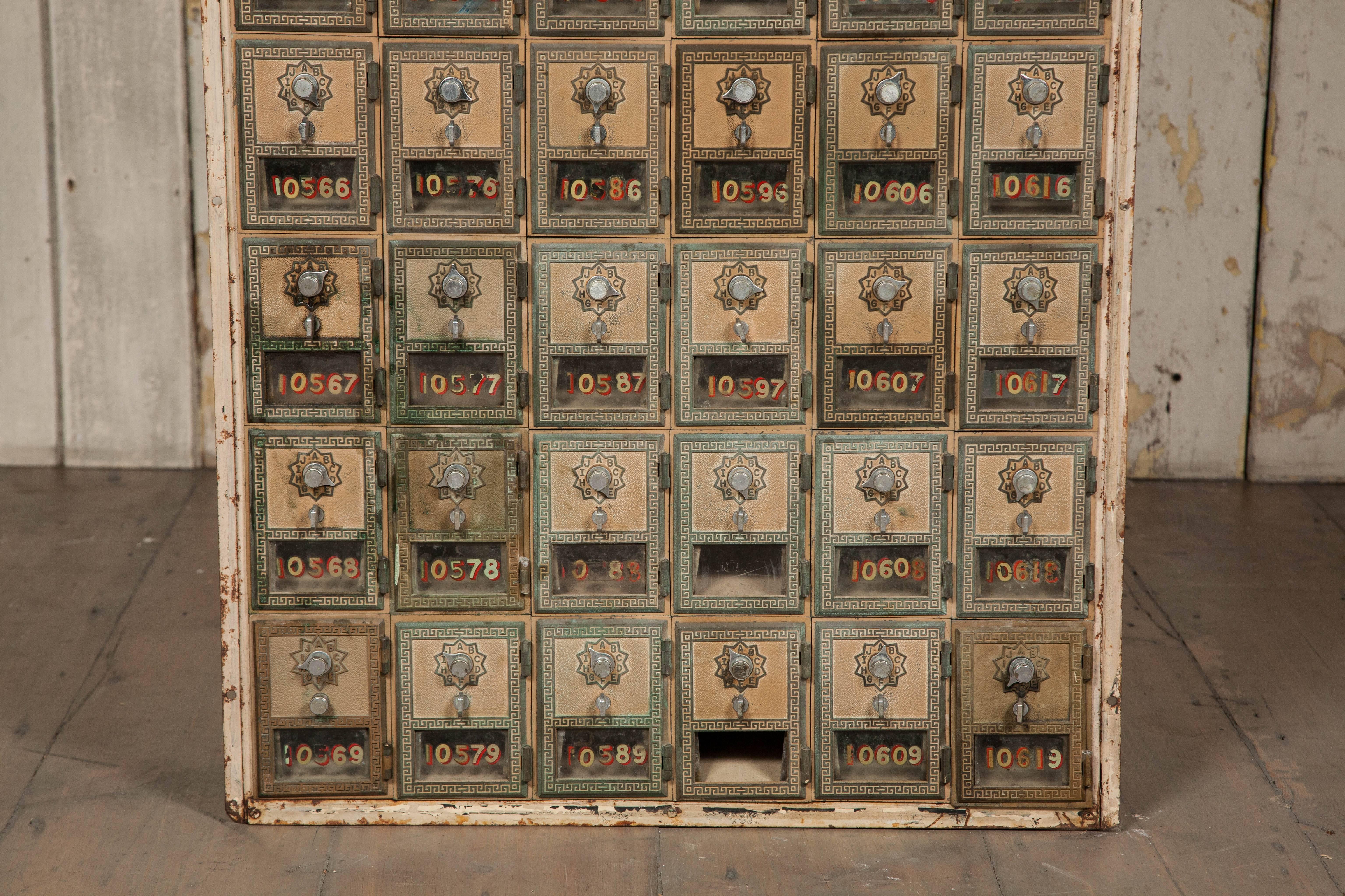 A bank of US Post Office mail boxes salvaged from a former US army barracks. The cabinet has a total of 54 numbered compartments. The lockers are decorated with a greek key border with the original numbers painted on the glass of most. 

We have