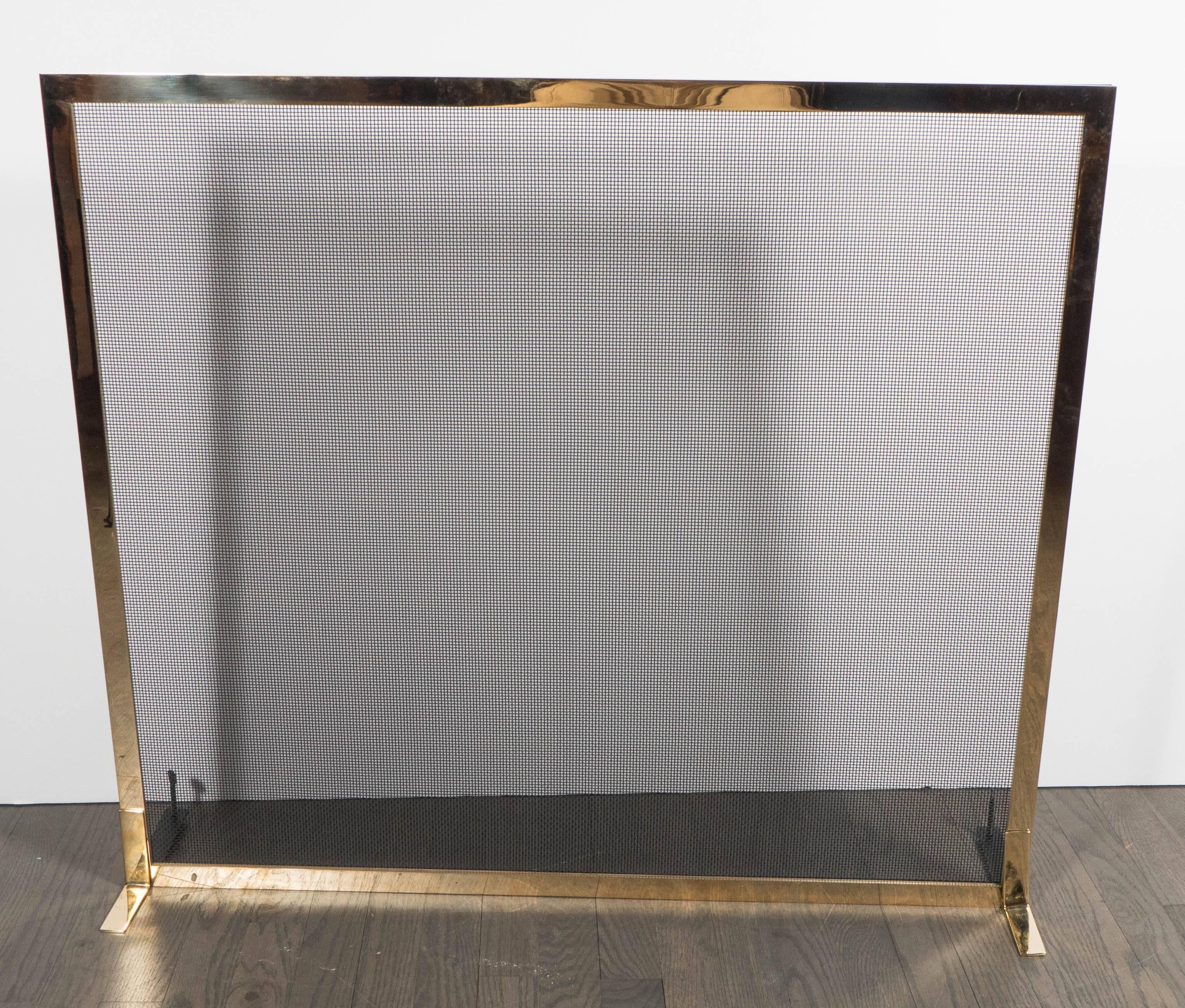 This elegant and understated fire screen was realized by artisans in New York State exclusively for us. It features a rectilinear frame in polished and lacquered brass with iron mesh in its center. With its austere form and clean, modernist lines,
