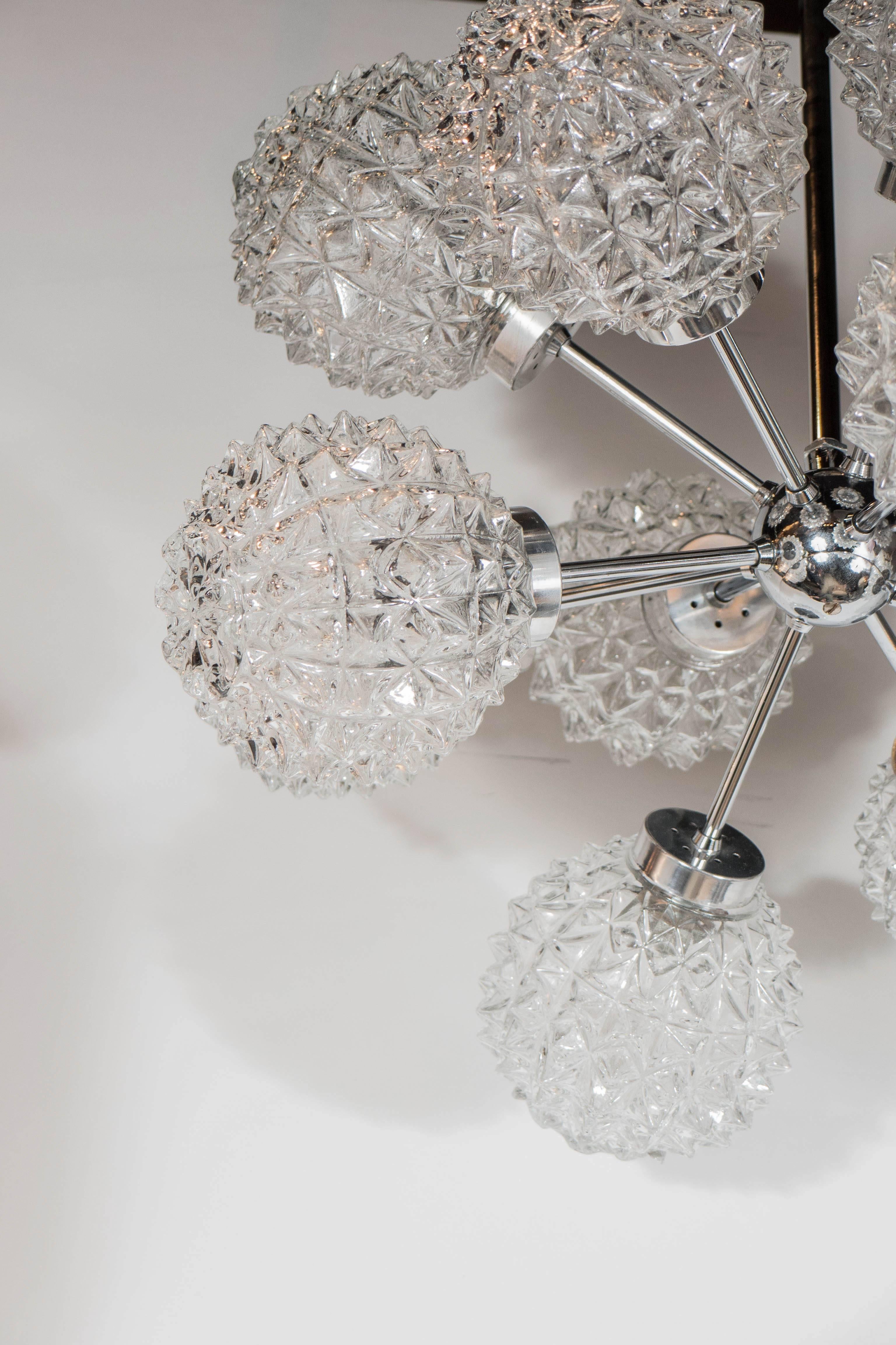 This stunning Mid-Century Modernist twelve-arm Sputnik chandelier by Richard Essig consists of a chrome frame, a central sphere from which the rods emanate; each rod has a spherical glass globe with a deep faceted texture. It has been newly rewired