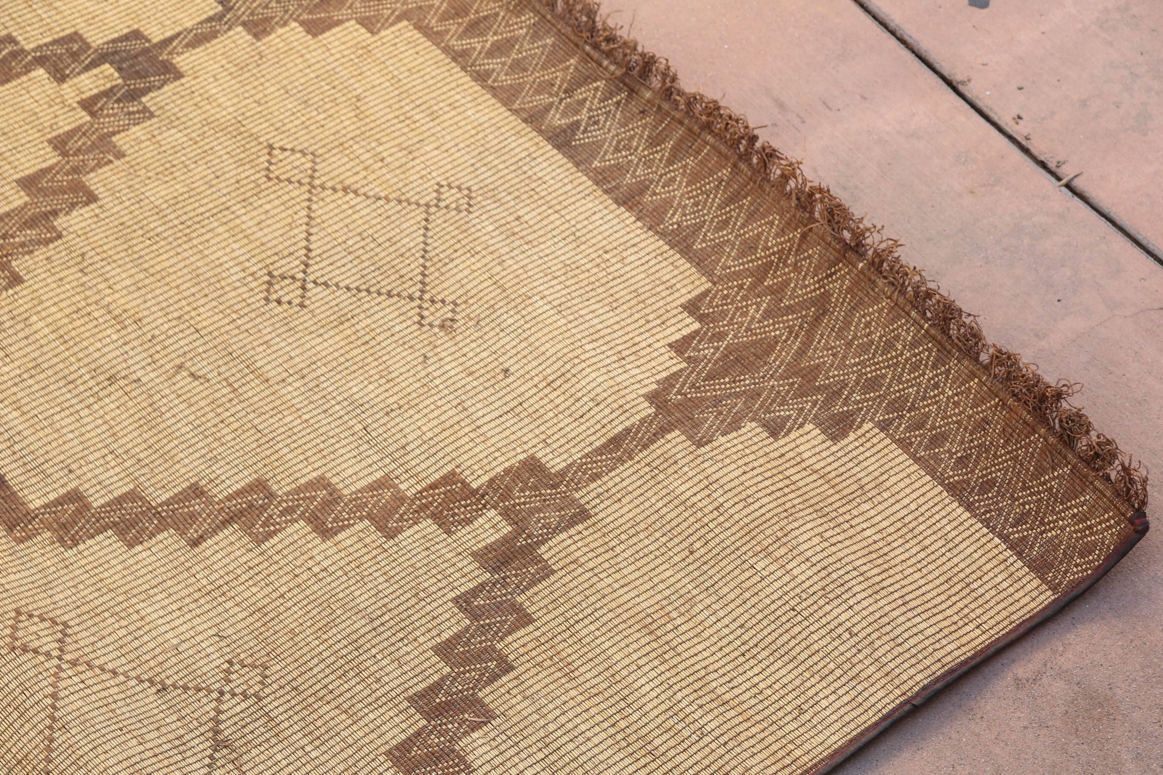 Moroccan Tuareg leather mats are made of dwarf palm tree fibers and handwoven with leather stripes, this are great to use indoor or outdoor, beautiful brown earth-tone colors. This vintage midcentury carpets are made in the desert of Morocco near