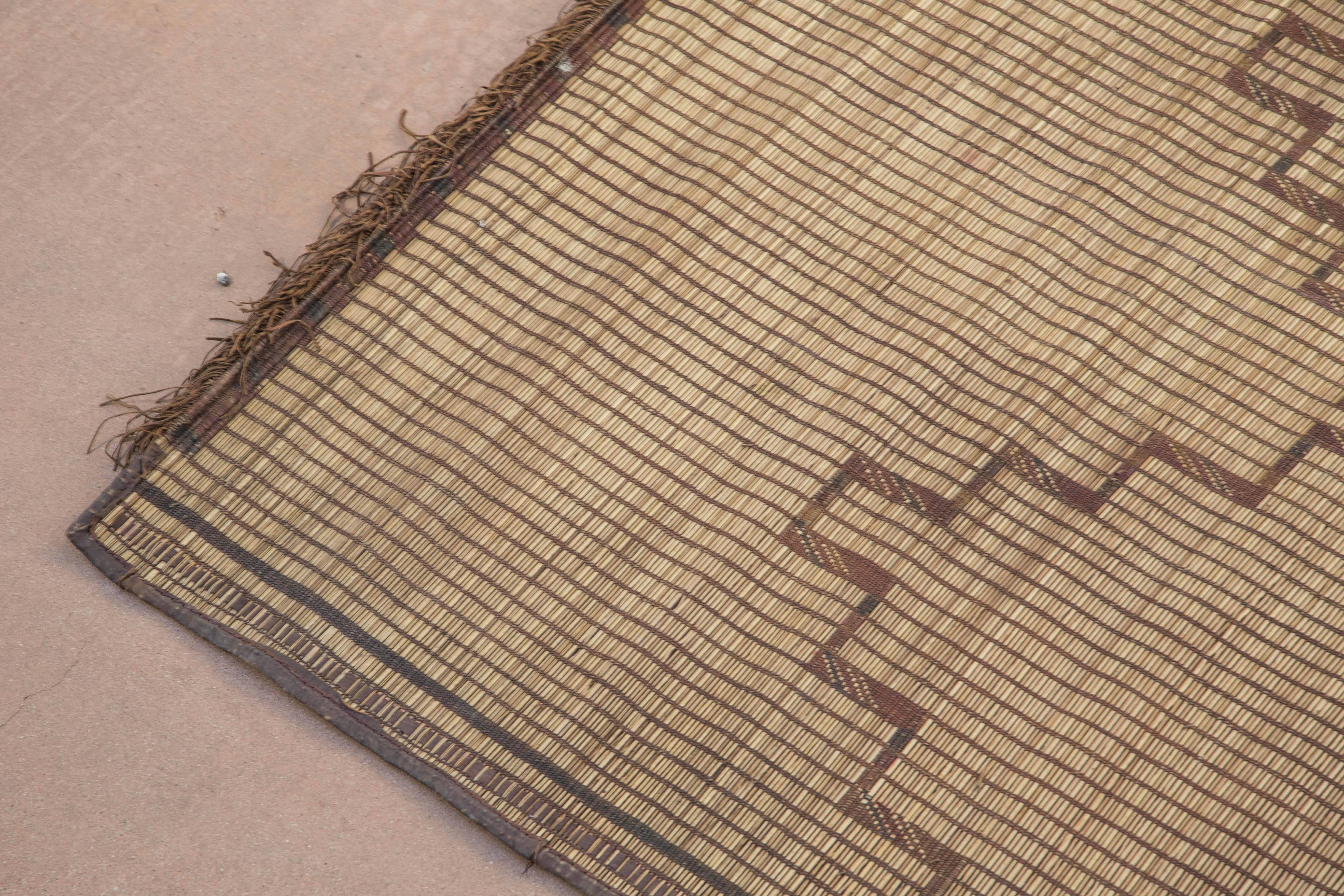 Moroccan Tuareg leather mats are made of dwarf palm tree fibers and hand-woven with leather stripes, this are great to use indoor or outdoor, beautiful brown earth-tone colors. This vintage mid century carpets are made in the desert of Morocco near