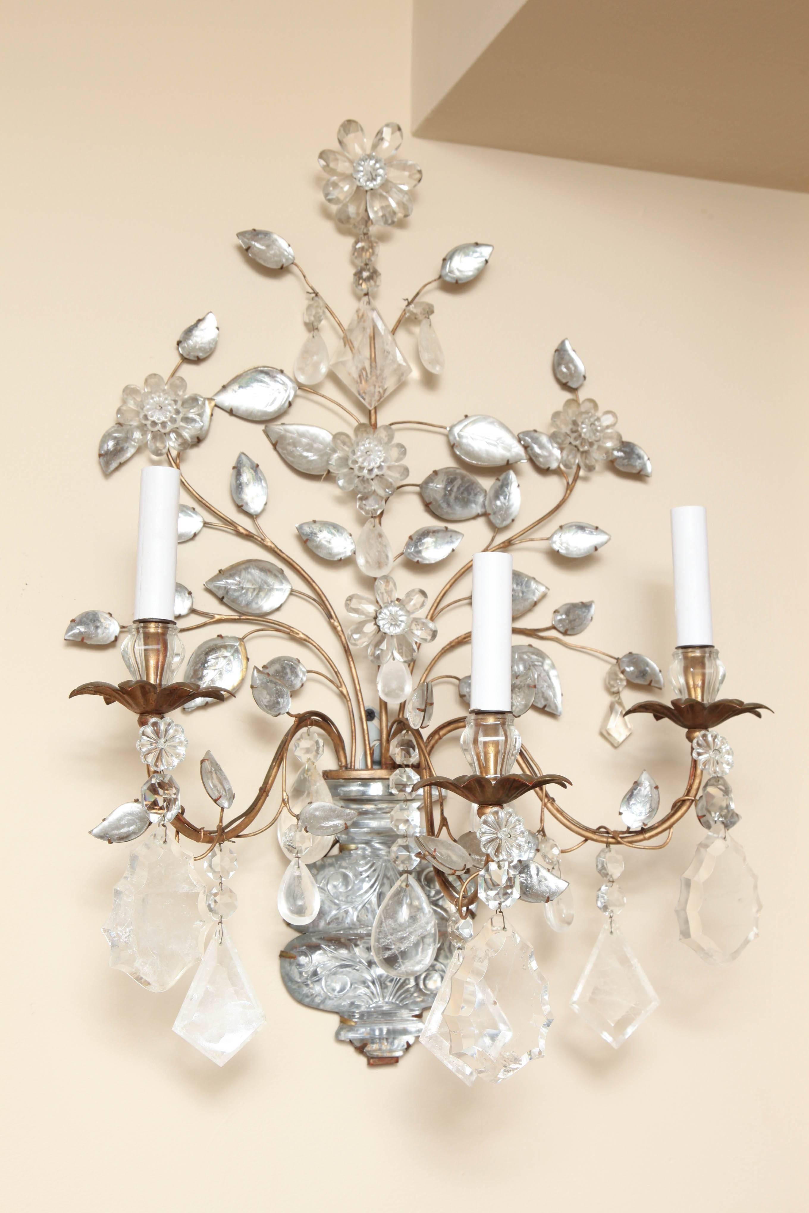 Pair of 3 Light French Bagues Louis XVI style wall sconces with carved glass vase shaped backplates issuing 3 branches with rock crystal, carved leaves, and flowers formed of beads. Each candle cup with leaf shaped metal bobeches. Circa 1950.