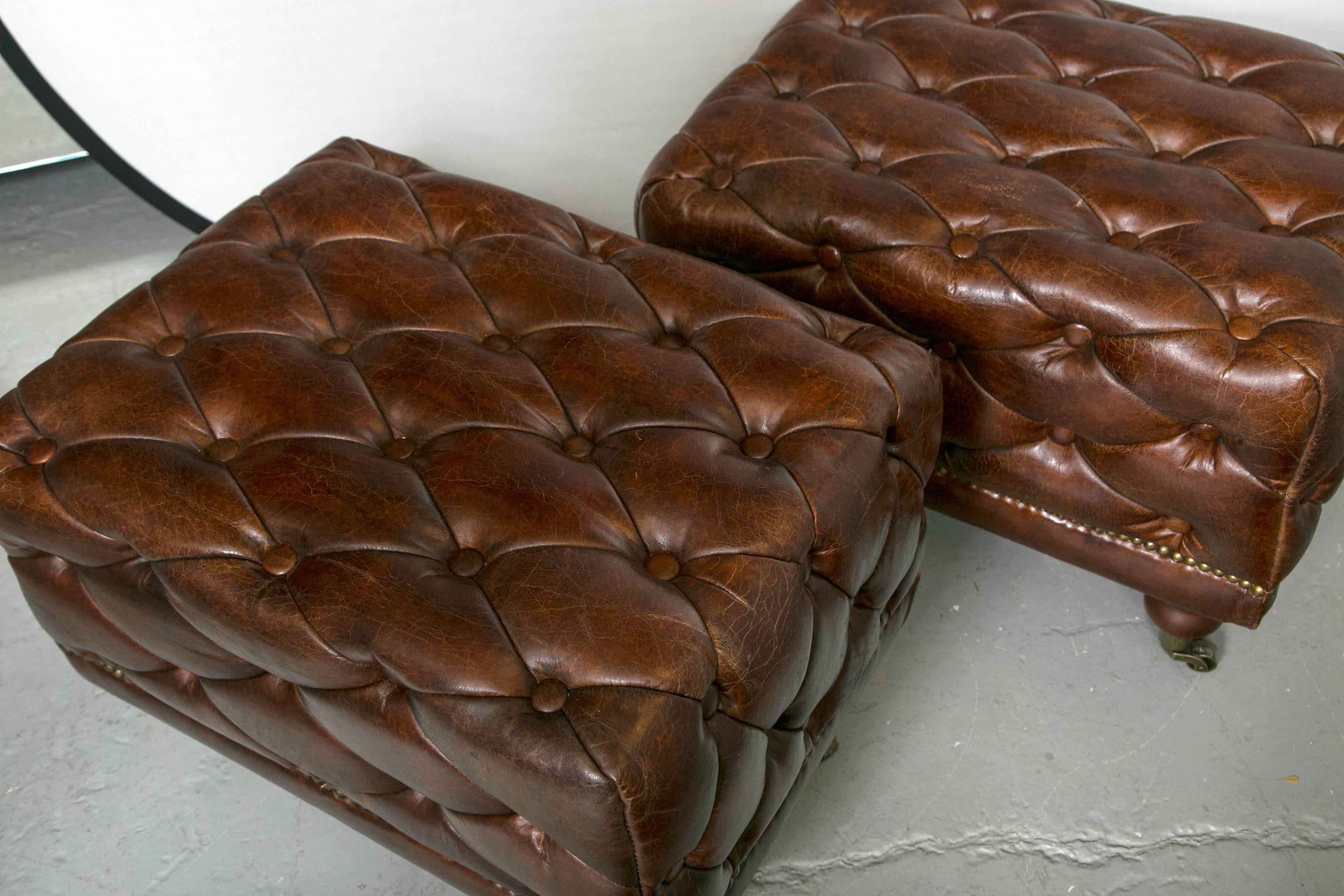 Pair of tufted leather Ottomans possibly by Ralph Lauren. Rectangular stools having tufted brown leather exterior with brass upholstery finishing nails around the base raised on four caster feet. Great leather - fabulous size and style! A hard to
