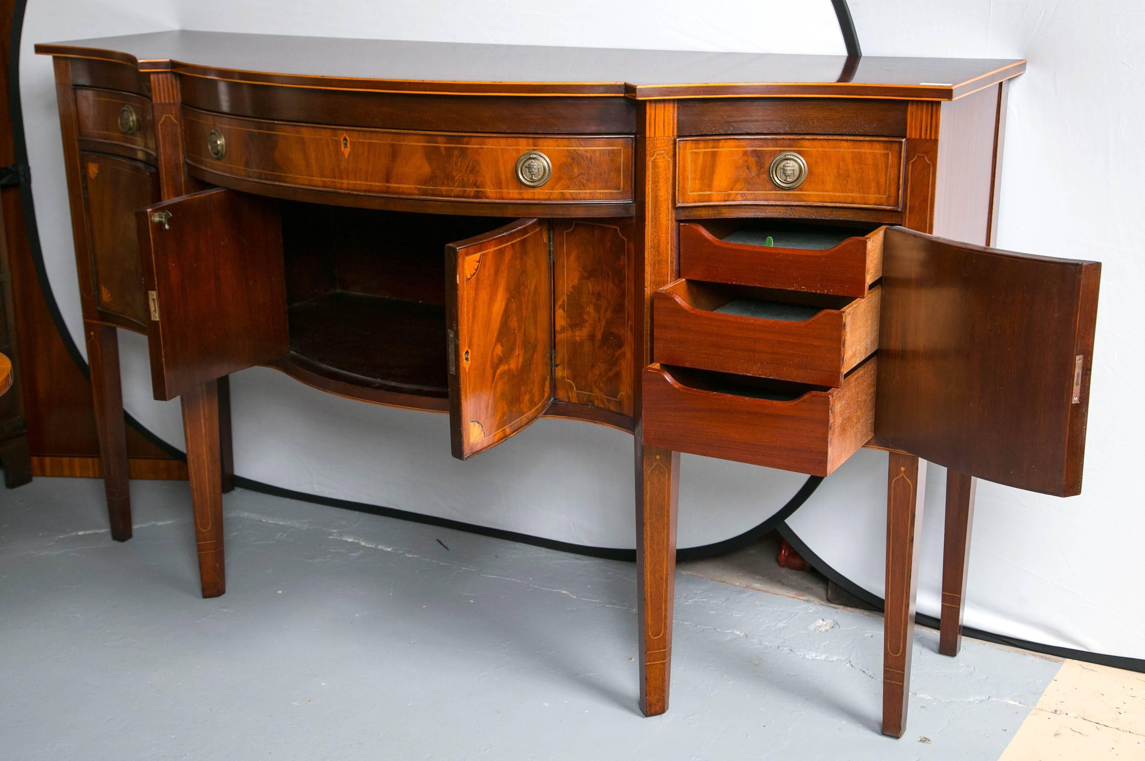 A solid mahogany sideboard handcrafted by Charak of buffalo. Beautiful flame mahogany buffet with three top drawers one large center drawer with two smaller flanking drawers. The bottom displaying four doors with beautiful inlaid satinwood opening