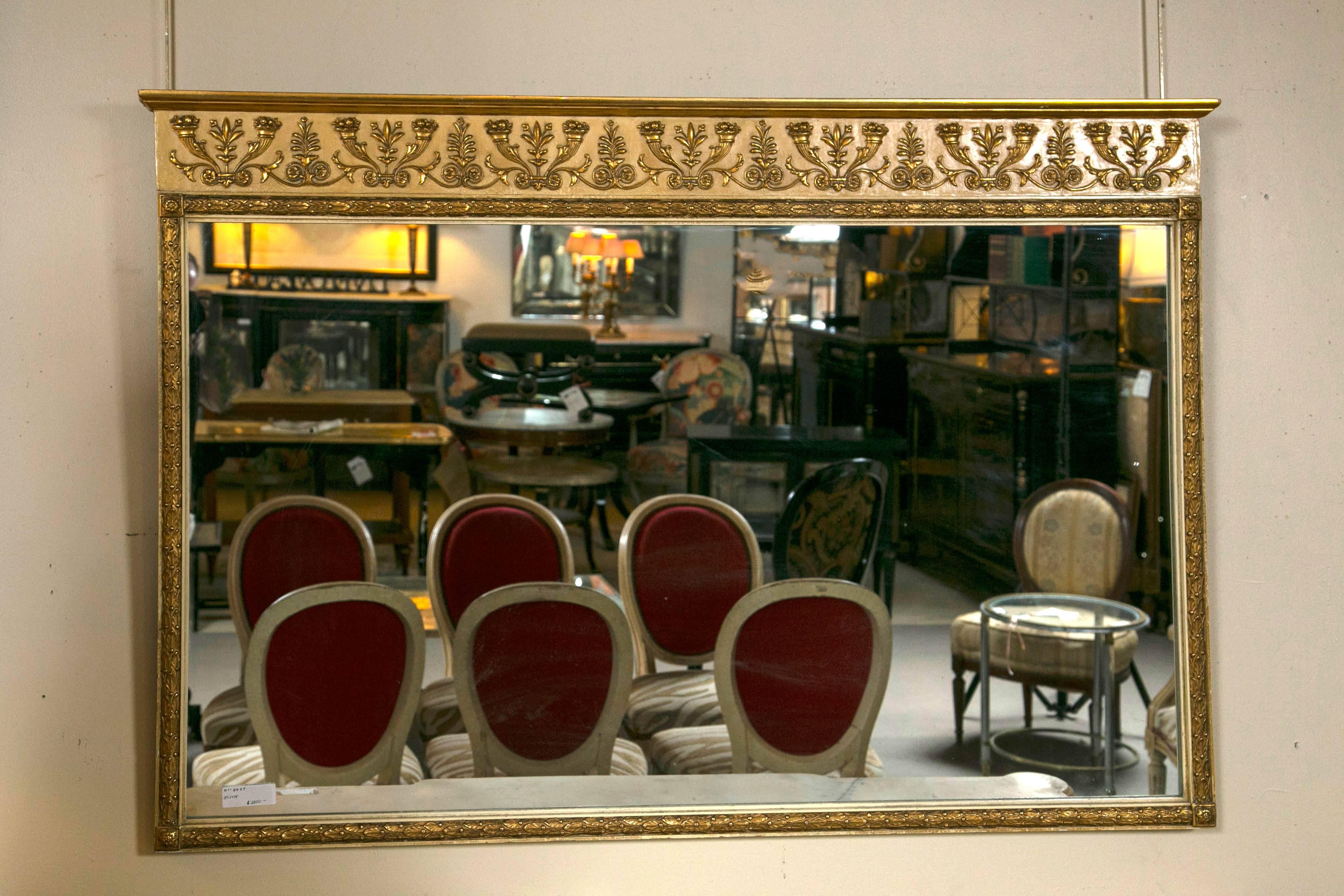 Schmieg & Kotzian gilt gold hand-carved rectangular mirror. The top apron above the mirror displays scroll and leaf with urns of splendid floral and florets. The clear glass mirror is surrounded by giltwood carvings of petite florets, vine and leaf
