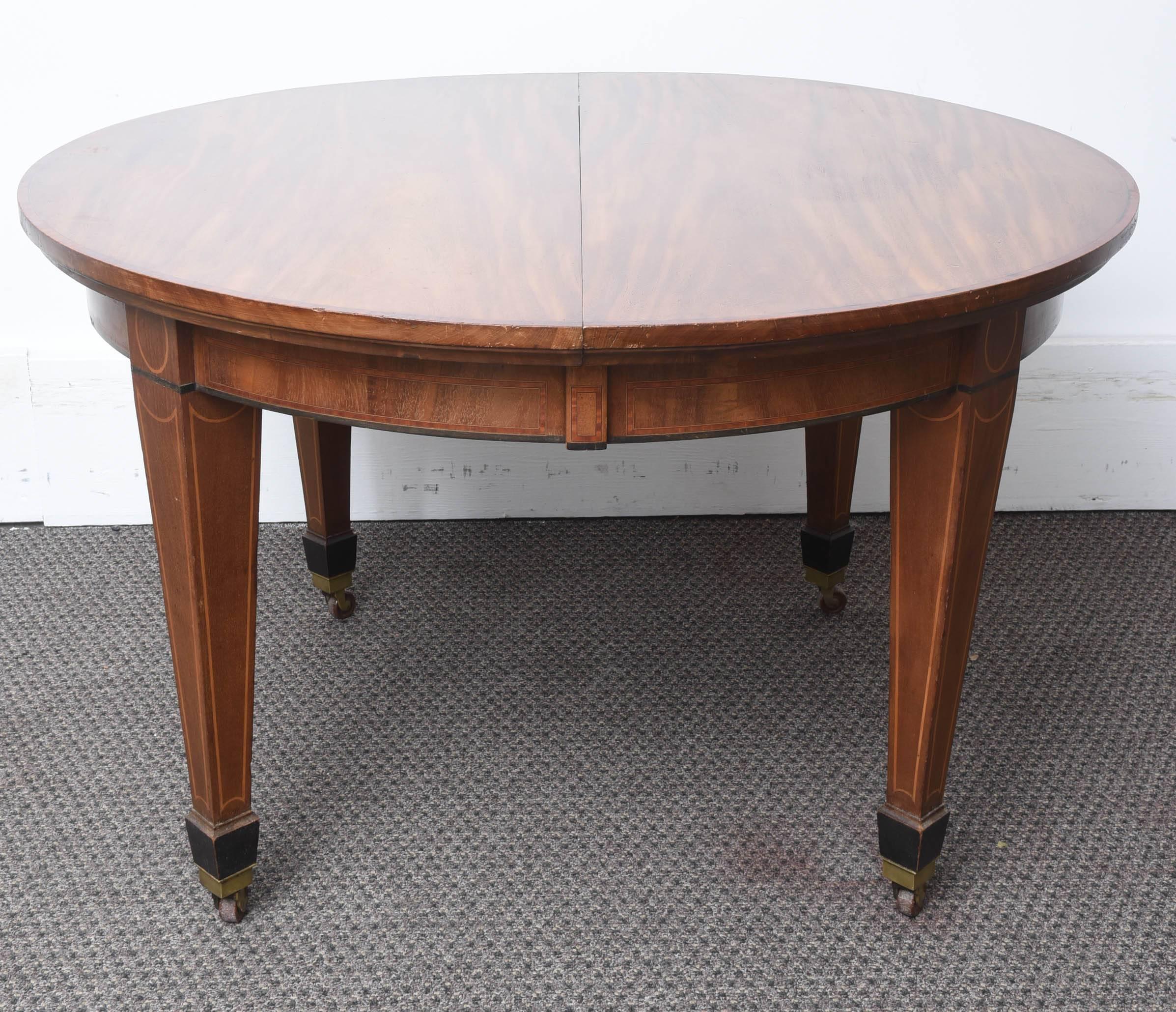 This is a superb mahogany dining table with two original leafs.
It sits on square tapered legs with satinwood inlay down the sides; to the bottom it has the original castors. Thee top is a flamed mahogany in a light color, the edges has satinwood