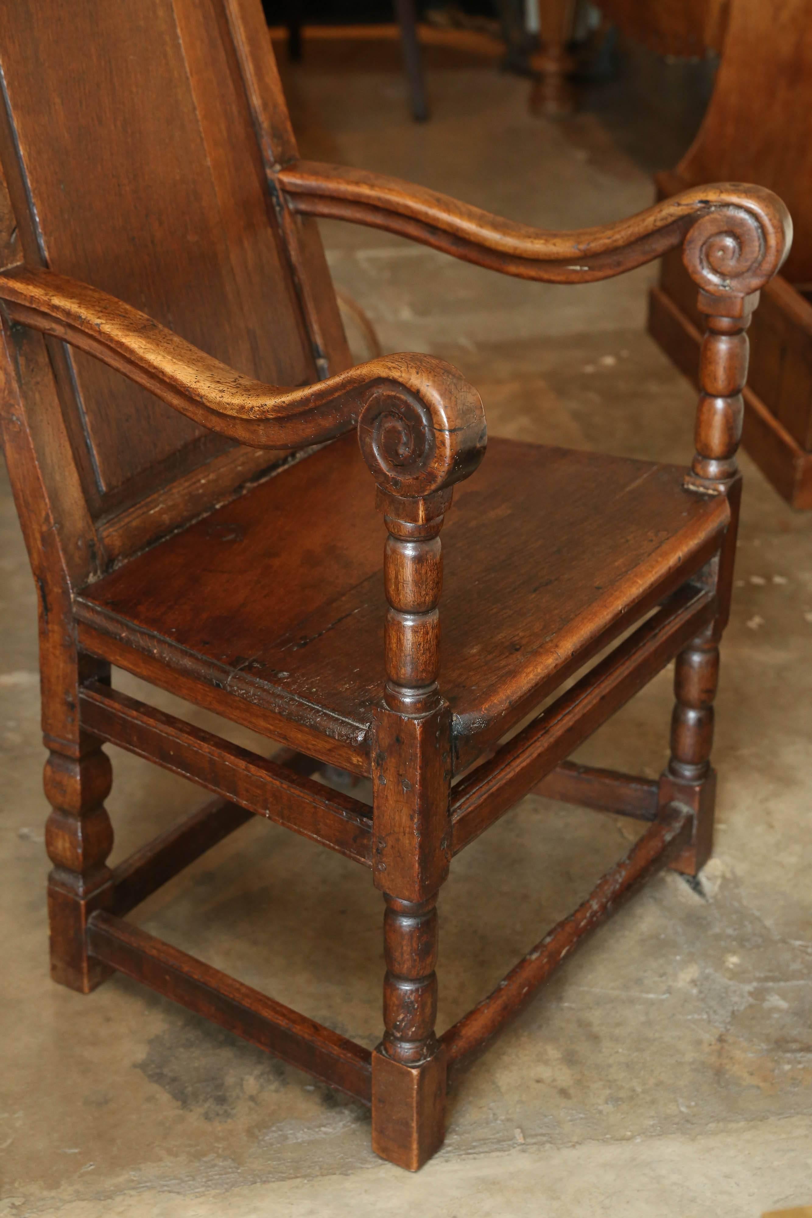 18th century oak welsh wainscot hall chair with beautifully worn arms from years of use. Simple design with a central carved detail at the top of the back. Great character in stretchers, as well. Very, very sturdy. Surprisingly comfortable.  Split