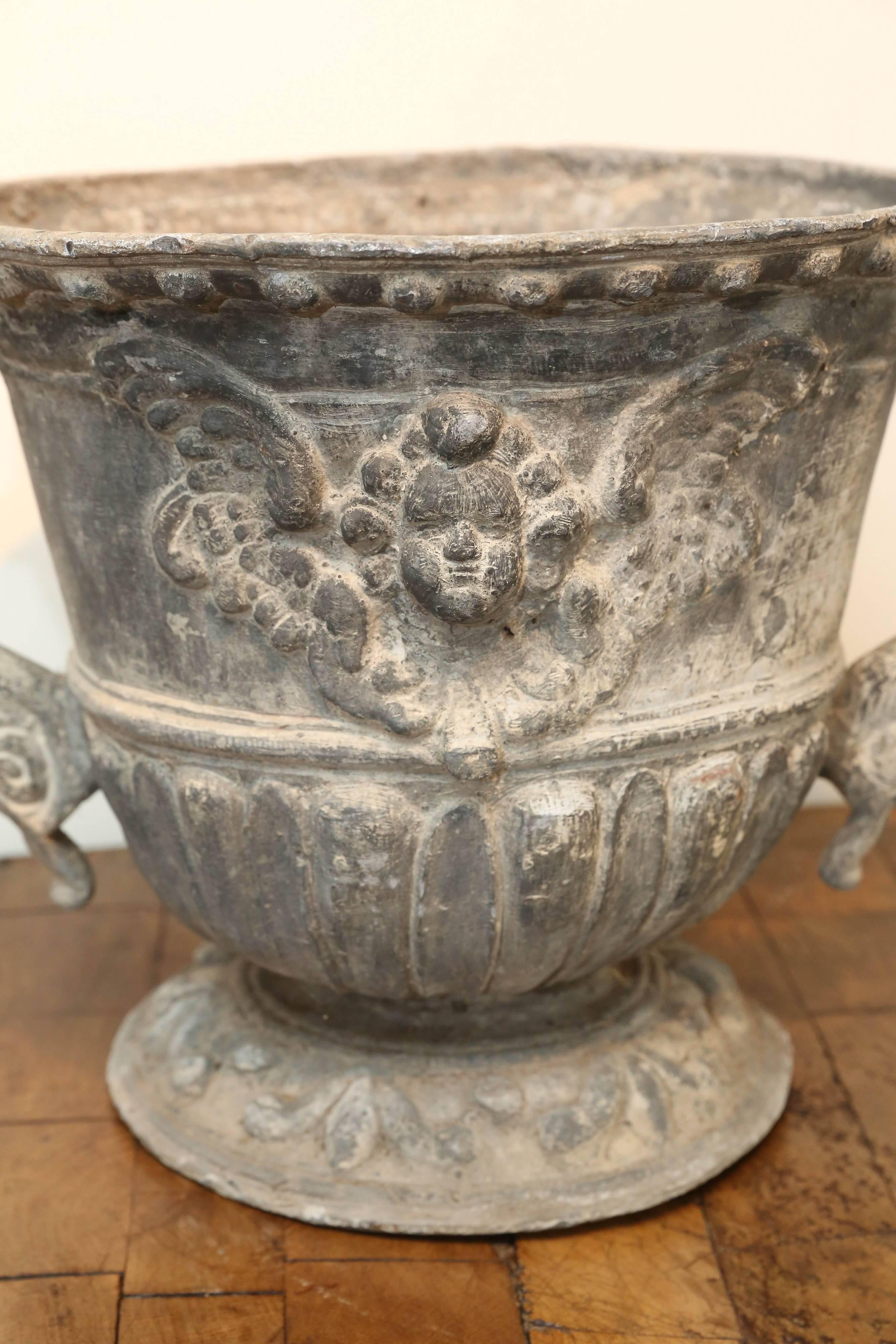 19th century English lead urn with griffin handles and angel face flanking front and back. Inside diameter: 10