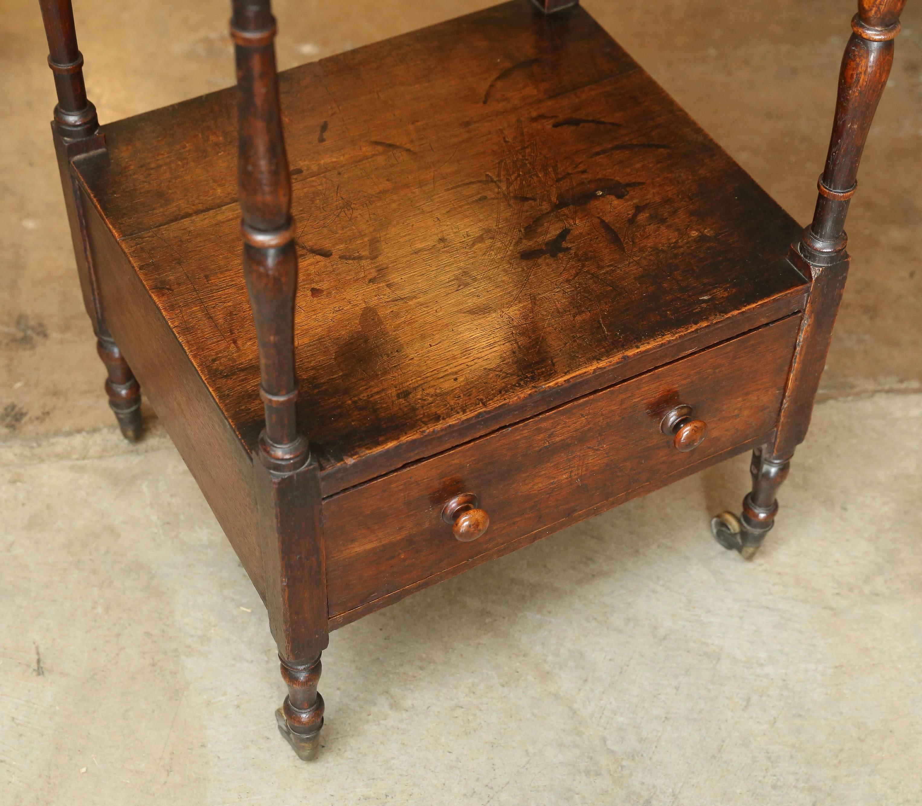 19th century whatnot with three shelves and bottom drawer. Oak and mahogany, circa 1820. Wheels are original.