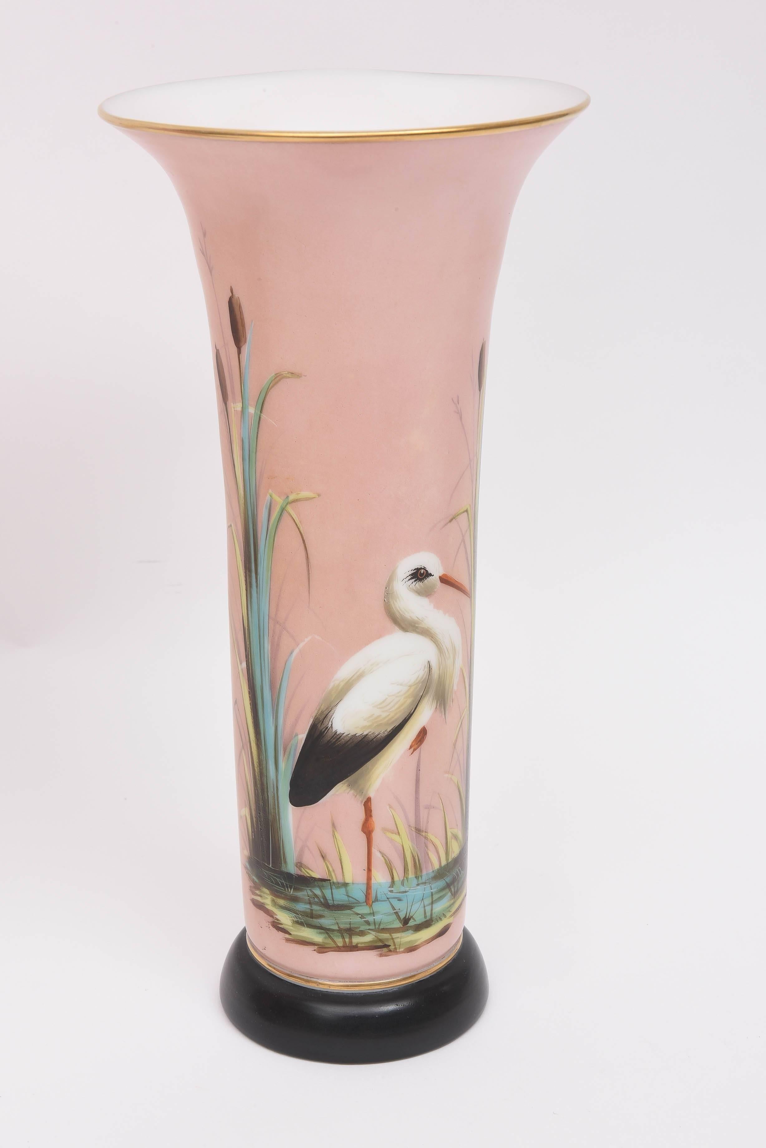 A hard to find pair of antique opaline glass vases, attributed to the storied  Baccarat factory of France. A wonderful pedestal base with vibrant hand painted exotic birds in full flora fauna. All designed on a soft pink ground. Nice white interior.