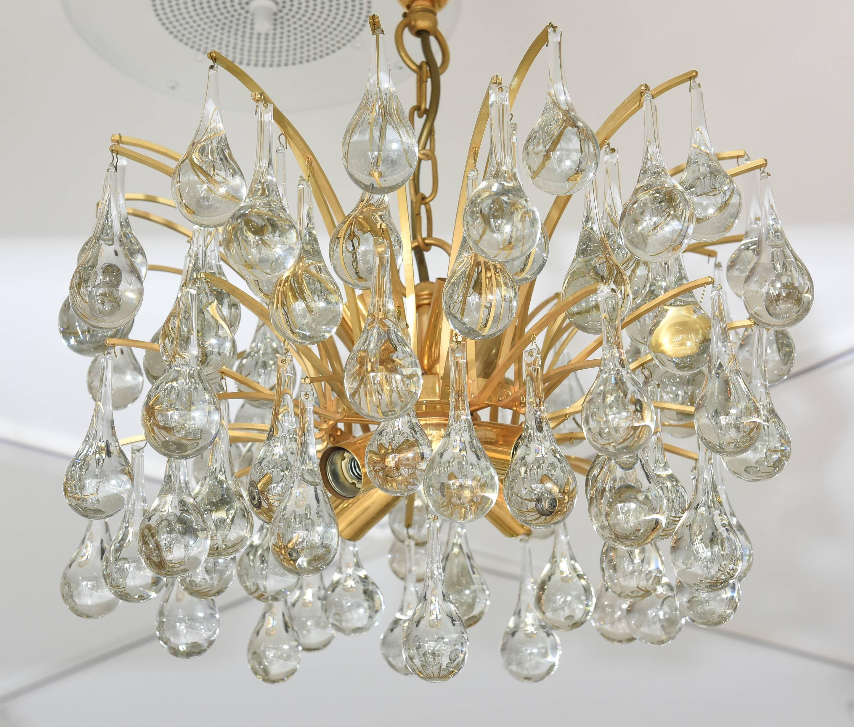 This amazing Hollywood-Regency style chandelier was made in the 1970s by the iconic firm Ernst Palme in the 1970s. The piece is gold-plated and the crystal prisms are in a tear-drop form.

Note: The last three photos will show that there are small