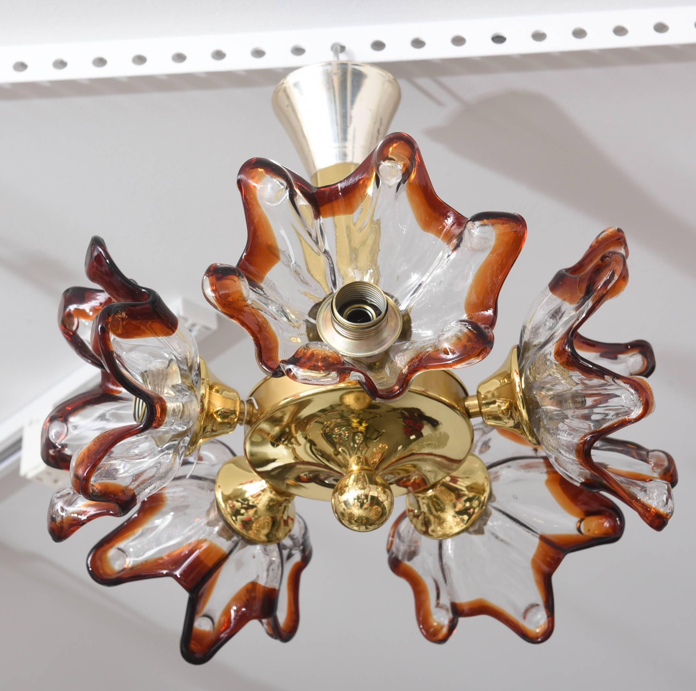 This amazing Mid-Century chandelier with its five Murano glass stylized floral blossoms in clear and amber-colors was created by the iconic firm Mazzega in the 1960s. The blossoms approximately measures 7" diameter x 7" depth.

Note: