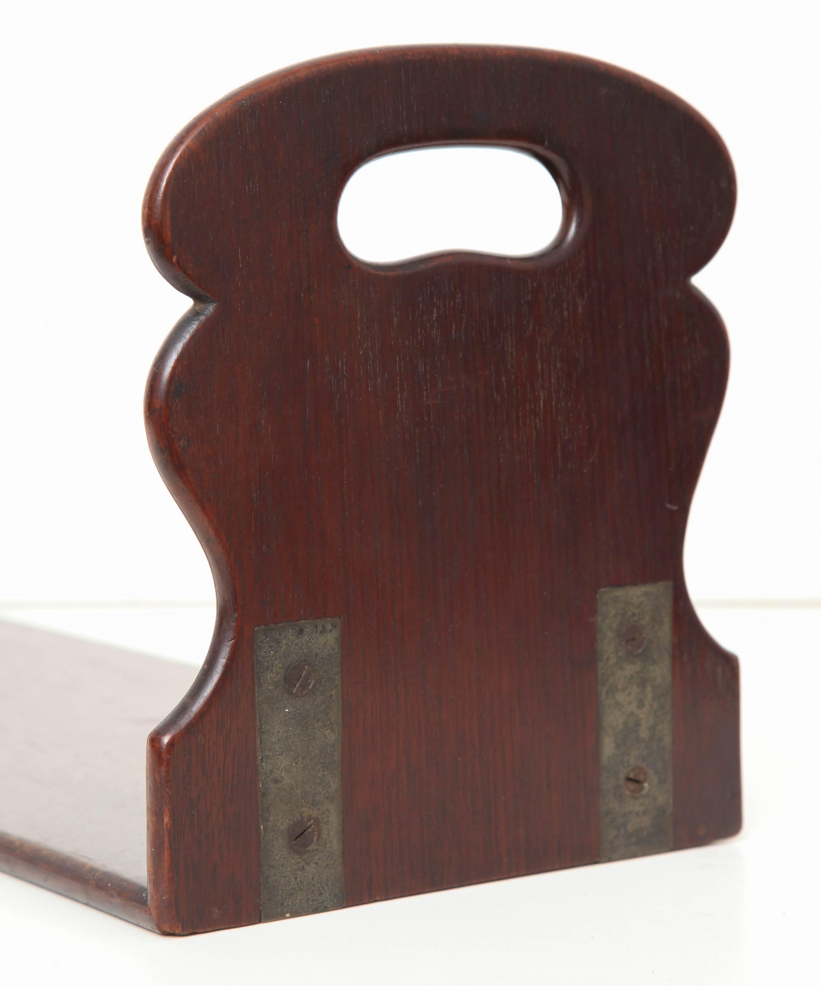 An early 19th century English mahogany book rest with shaped ends and pierced carrying handles.