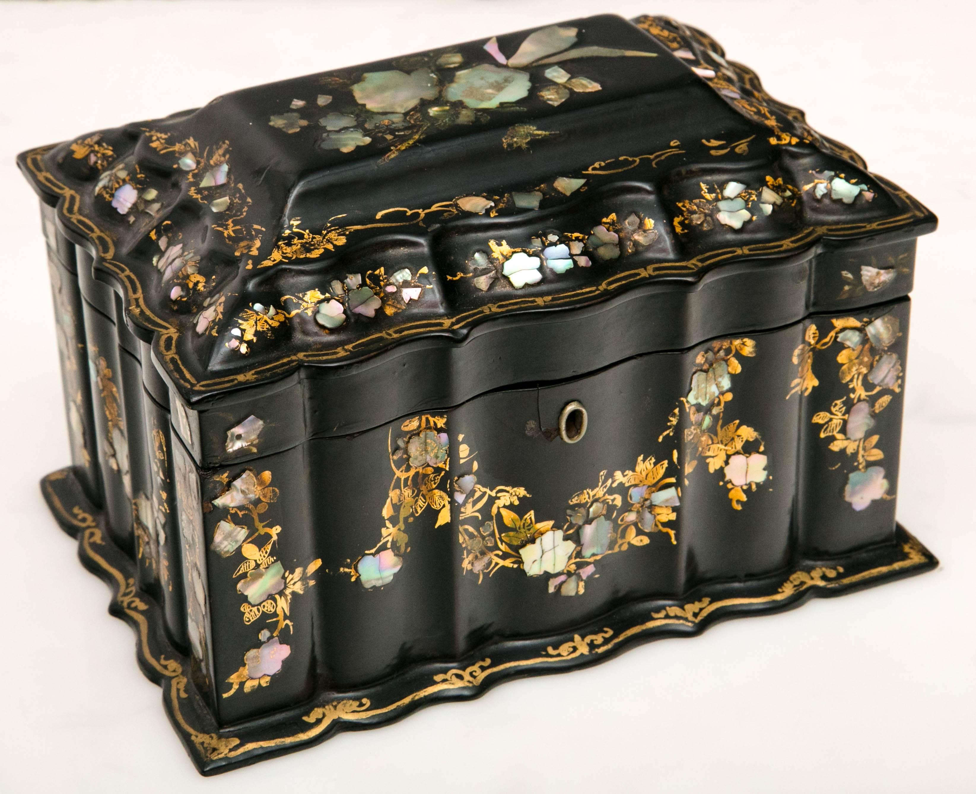 An antique papier-mâché tea caddy featuring mother-of-pearl and Abalone. The Mid-Victorian caddy with has two interior compartments for tea. The top features a design with a central floral display with floral vine detail throughout.