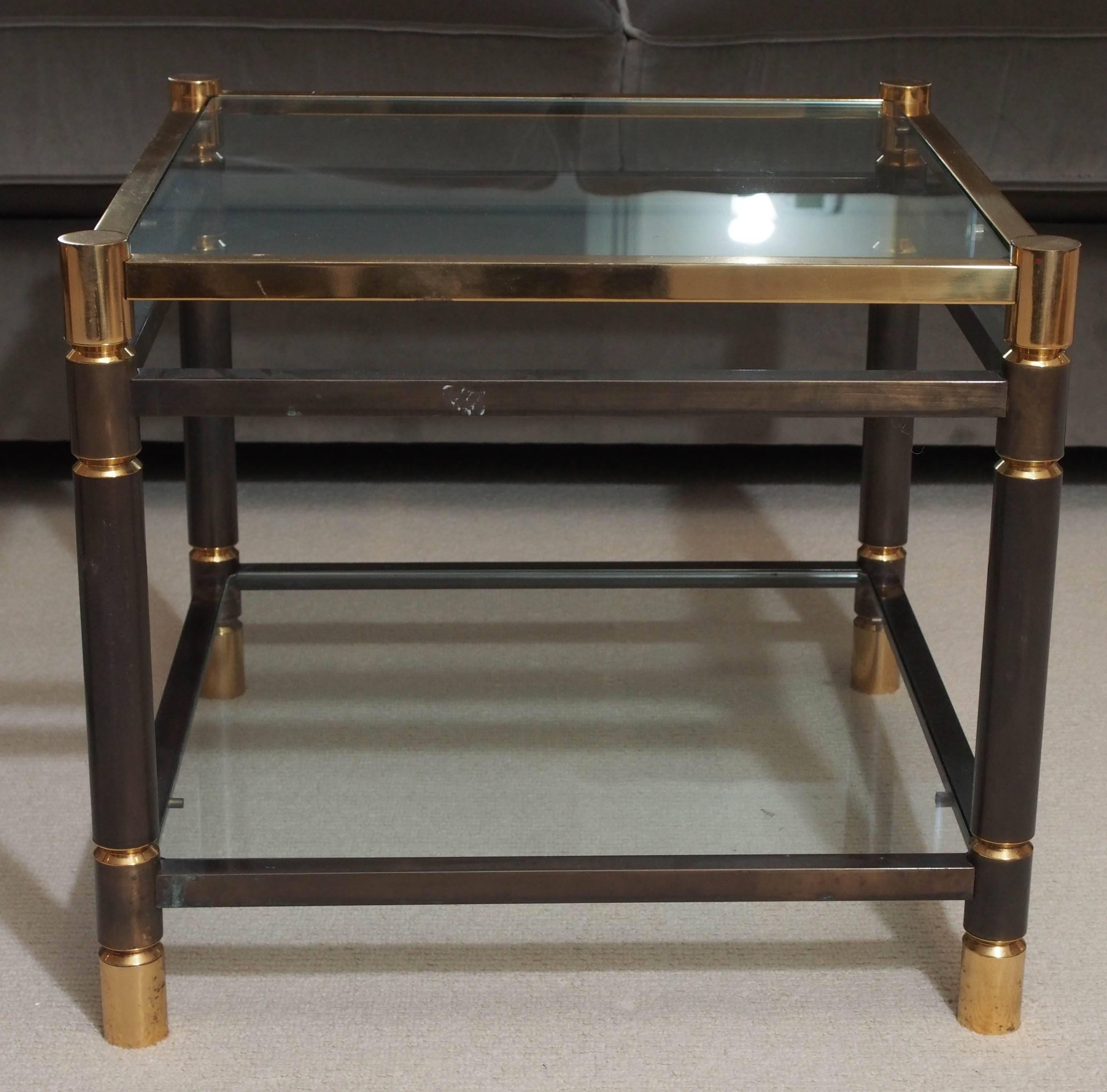 Pair of handsome two-tier side tables in turned solid steel with golden plate accents; the plateaux in clear glass; attributions to both Maison Charles and Maison Jansen.