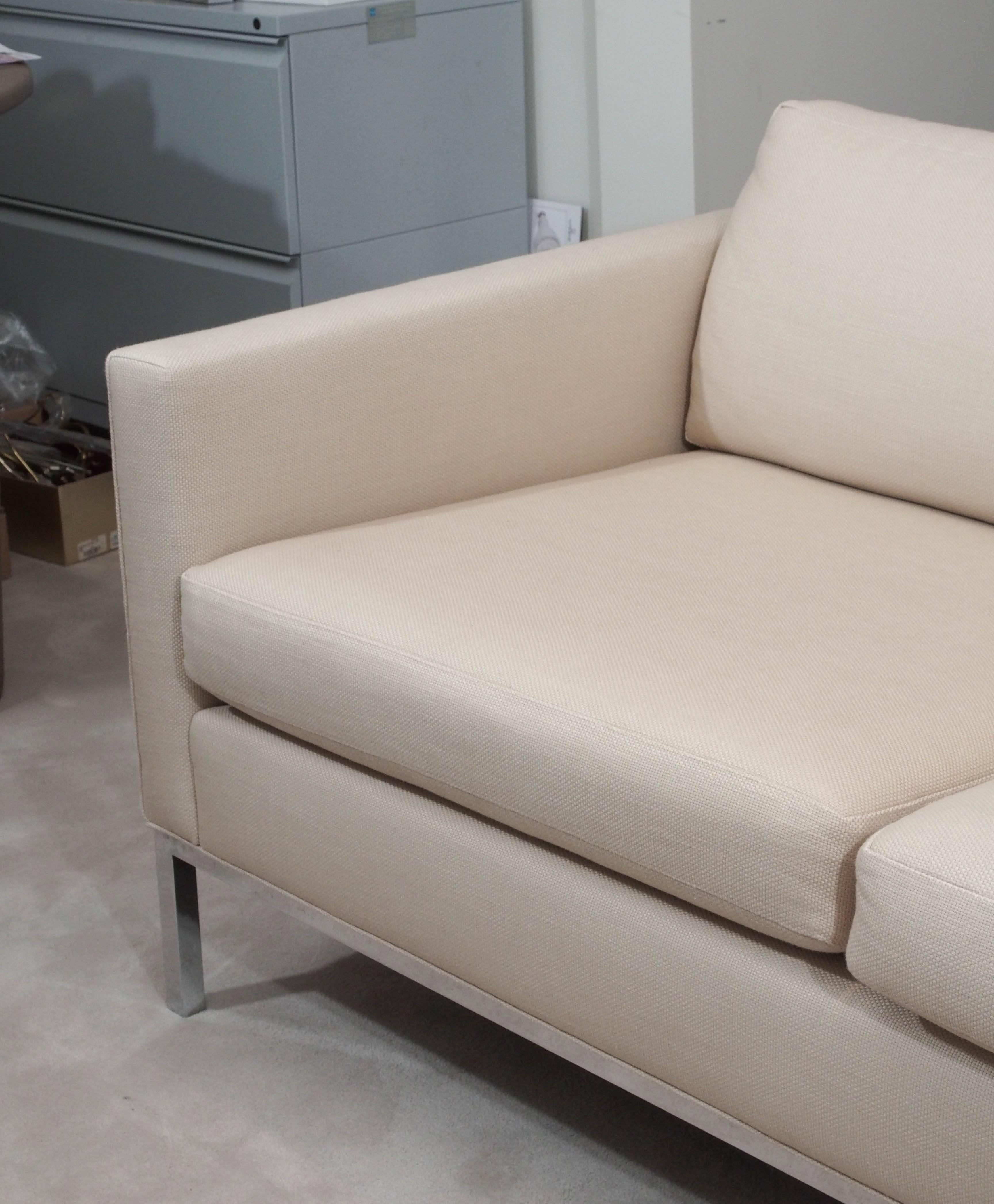 Handsome two-seat sofa in the style of Knoll; full-surround chrome-plated steel base; loose foam seat and back cushions; the whole upholstered in beige cotton weave.