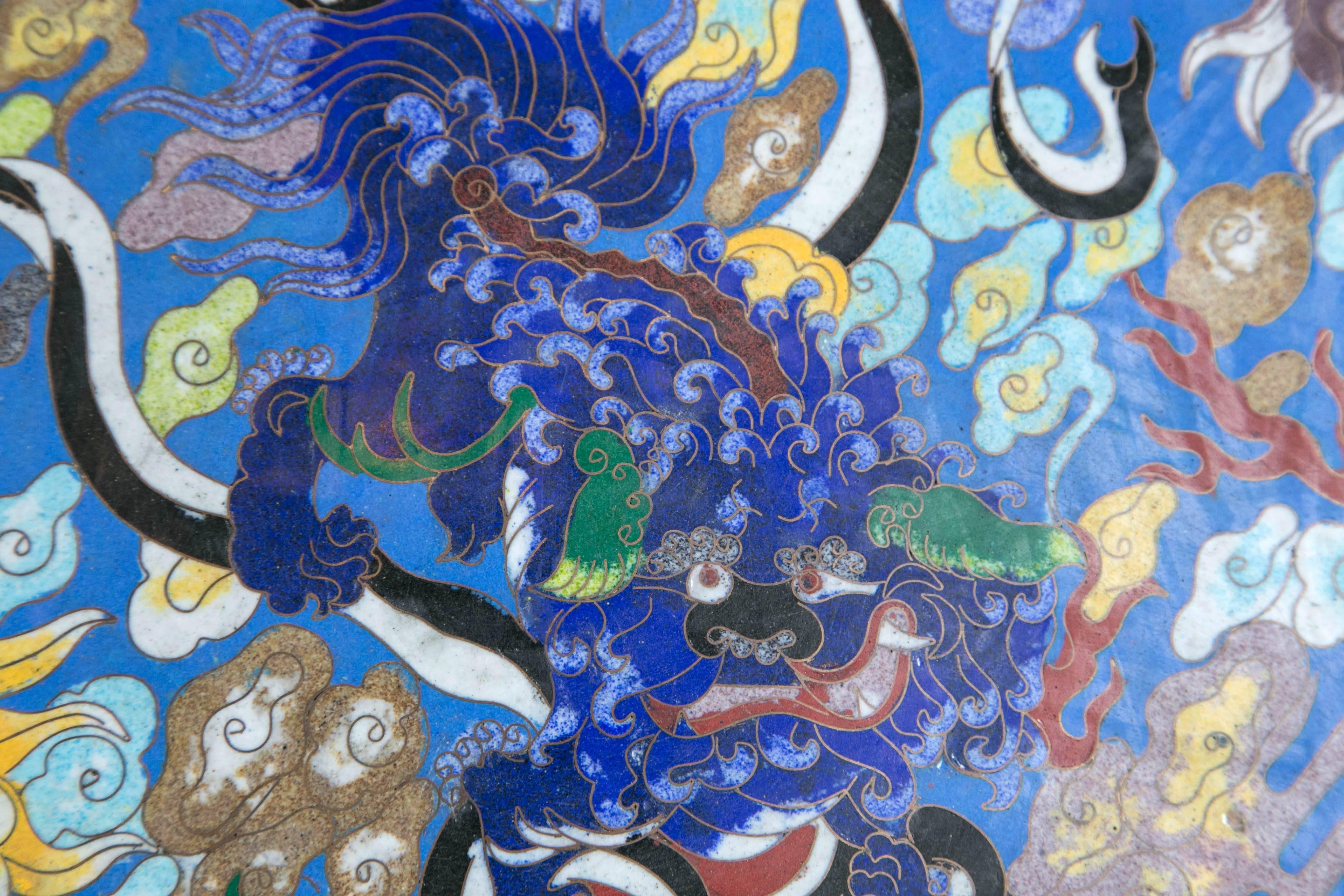 With a scalloped rim, dark red ground border with multi colors, a blue ground center with Chinese motifs of clouds, foo dogs and dragons, in varying colors, centered by a darker blue foo dog.  Though Chinese in    style, probably of Japanese origin.