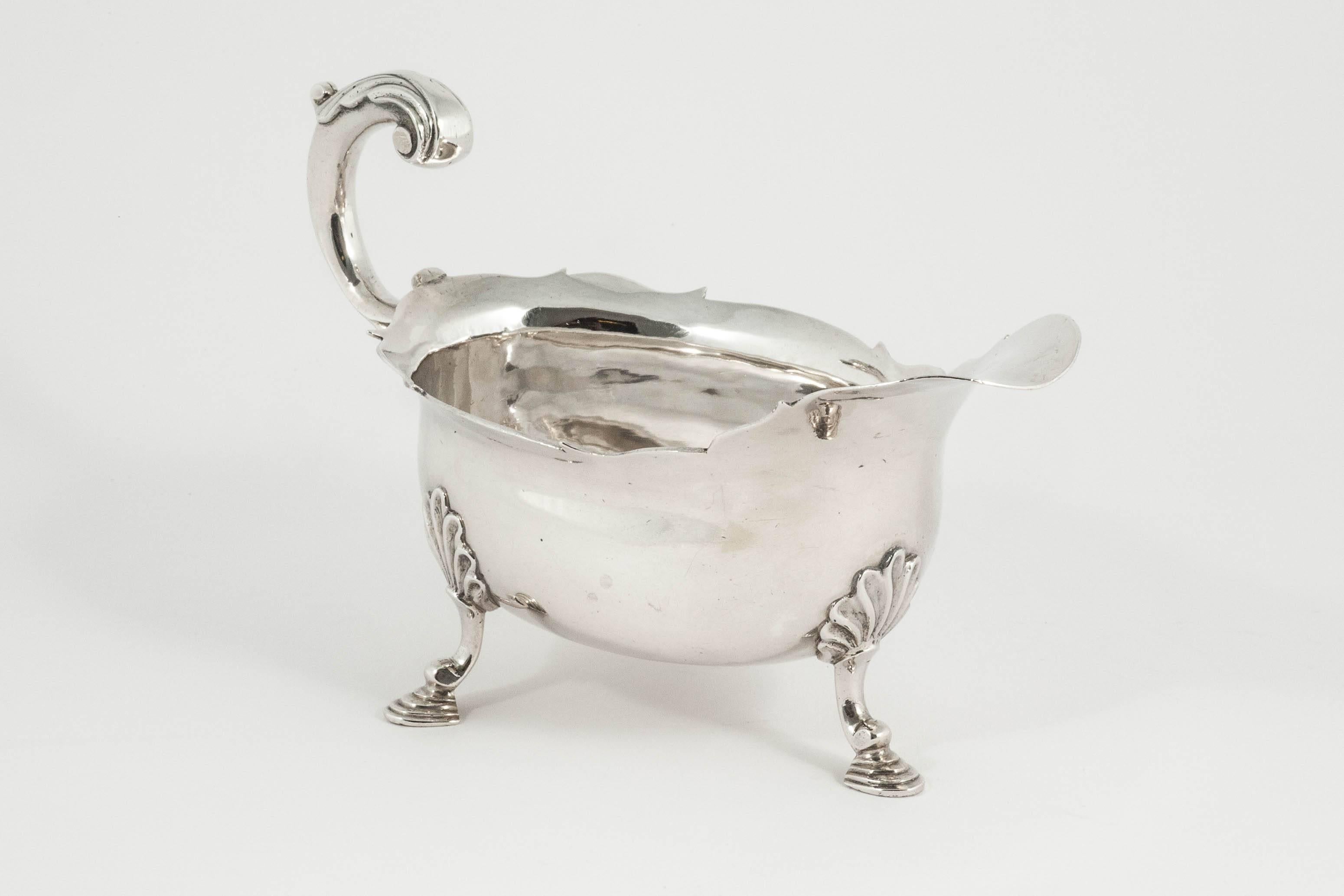 A fine and original pair of early George III sterling silver sauce boats or gravy boats in a classic Georgian style with wavy cut rims, cast scroll handles with leaf caps, and each on three cast feet with shell tops. This pair is in lovely condition