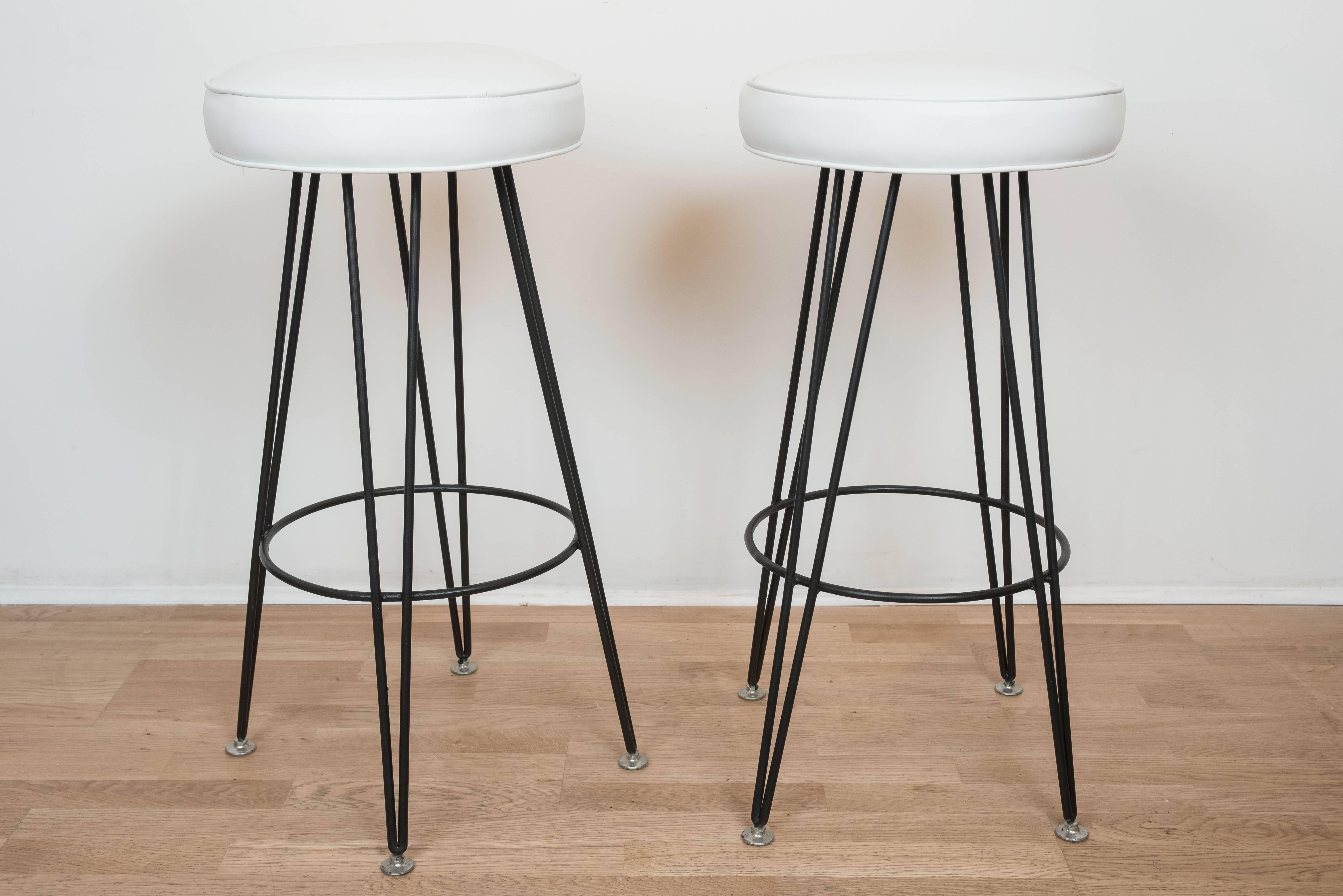 A hip set of four black painted metal stools with new white faux leather
upholstery.
