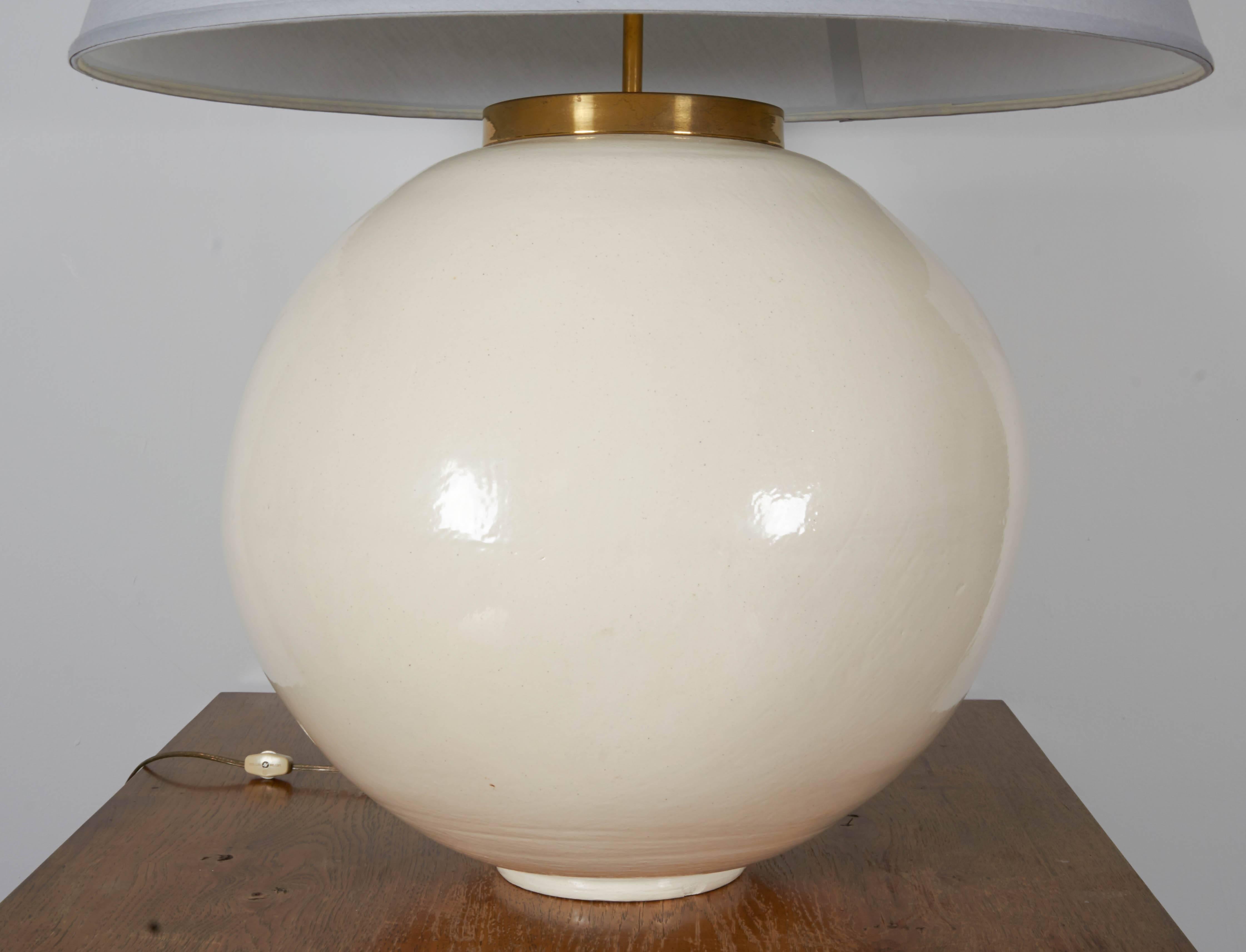 Monumental, cream-colored, ceramic globe lamp with custom grey linen shade and brass hardware. Very impressive scale.