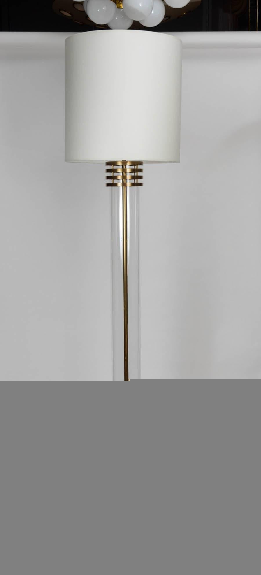 Elegant pair of floor lamps made of patinated bronze and glass. Composed of square feet and bronze rings setting a tall glass tube for a revisited antic aspect. The height of the upper stem holding the lights is adjustable.

Two sources of light