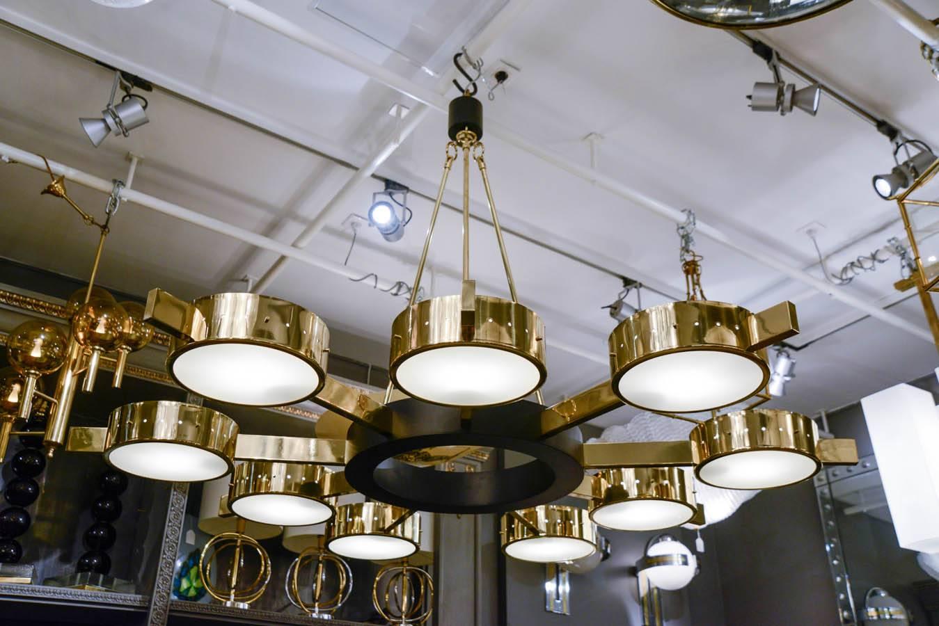 Large chandelier made of black enameled metal and brass, round shaped with nine arms each holding a source of light framed between two discs of glass.

Galerie Glustin Luminaires Creation.
