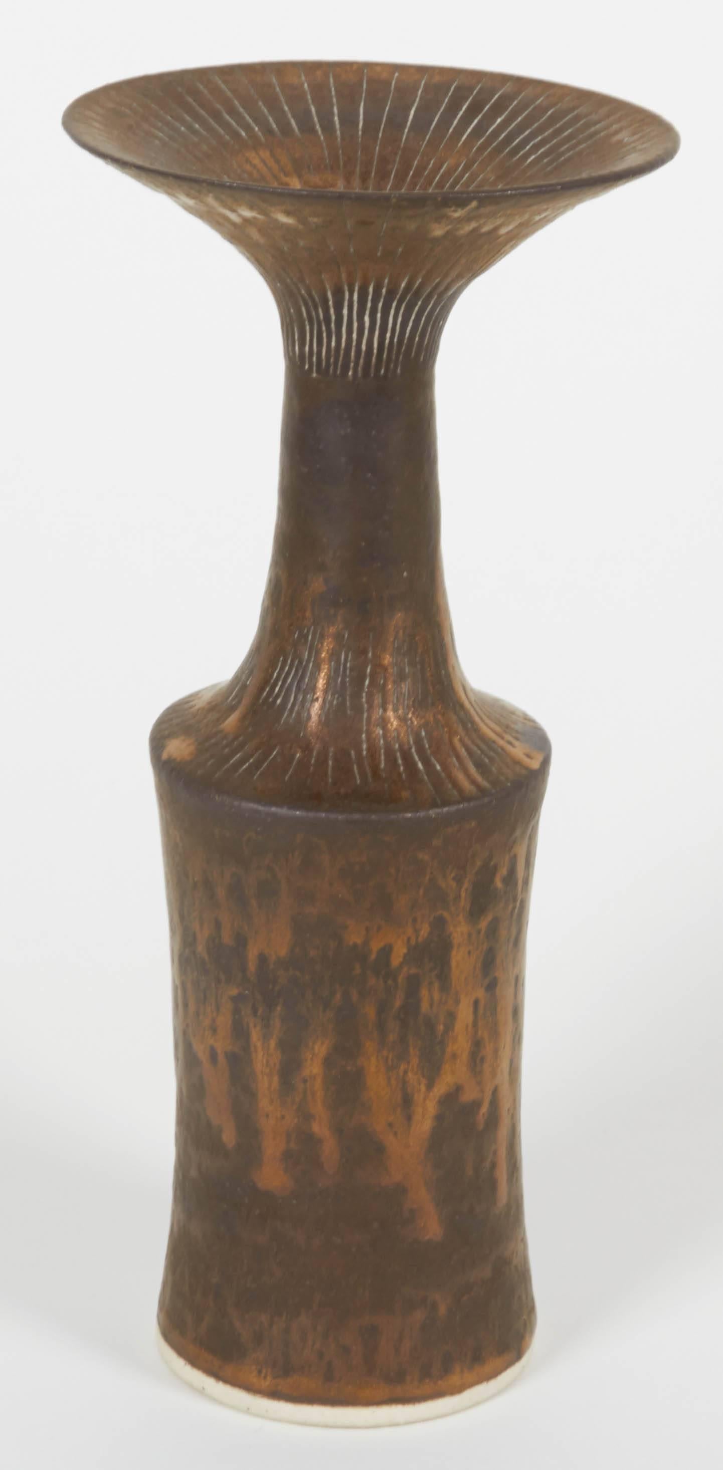A sculptural flared rim stoneware vase by sculpture/ artist Dame Lucie Rie. The flared earthy bronze rim with intermittent Sgraffito along the neck to shoulder expresses deeply the technical and creative savoir faire of Lucie Rie.

