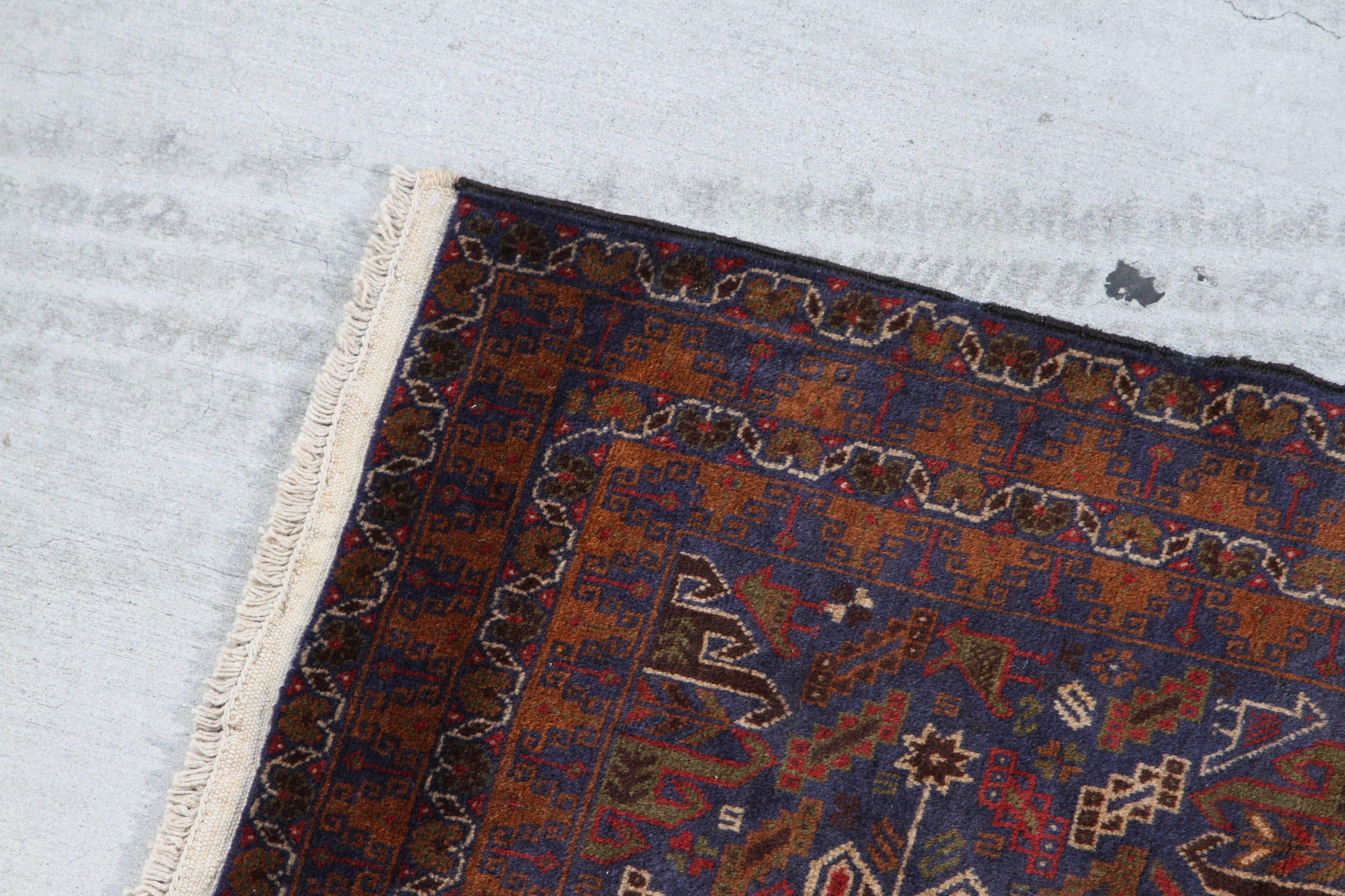 Antique Baluchi rug with large flowers in the center and repeating swirl pattern around the edges. Baluchi carpets are handmade carpets originally made by Baluch nomads, living near Iraq, Pakistan and Afghanistan.