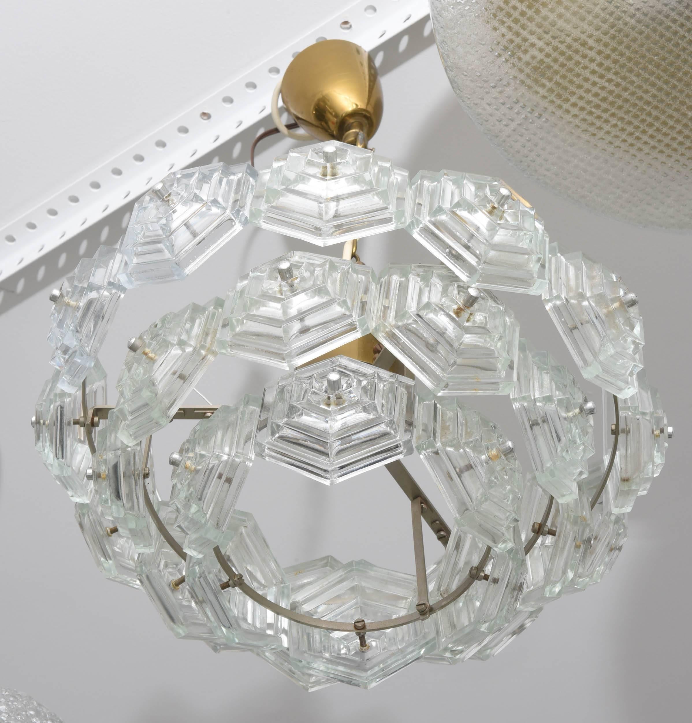 This beautiful Mid-Century Modern chandelier was created in the 1960s in Austria. It has a total of 27 hexagonal shaped molded-faceted glass prisms and brass trim. 

Note: The main body of the chandelier is approximately 5 3/4" in height x