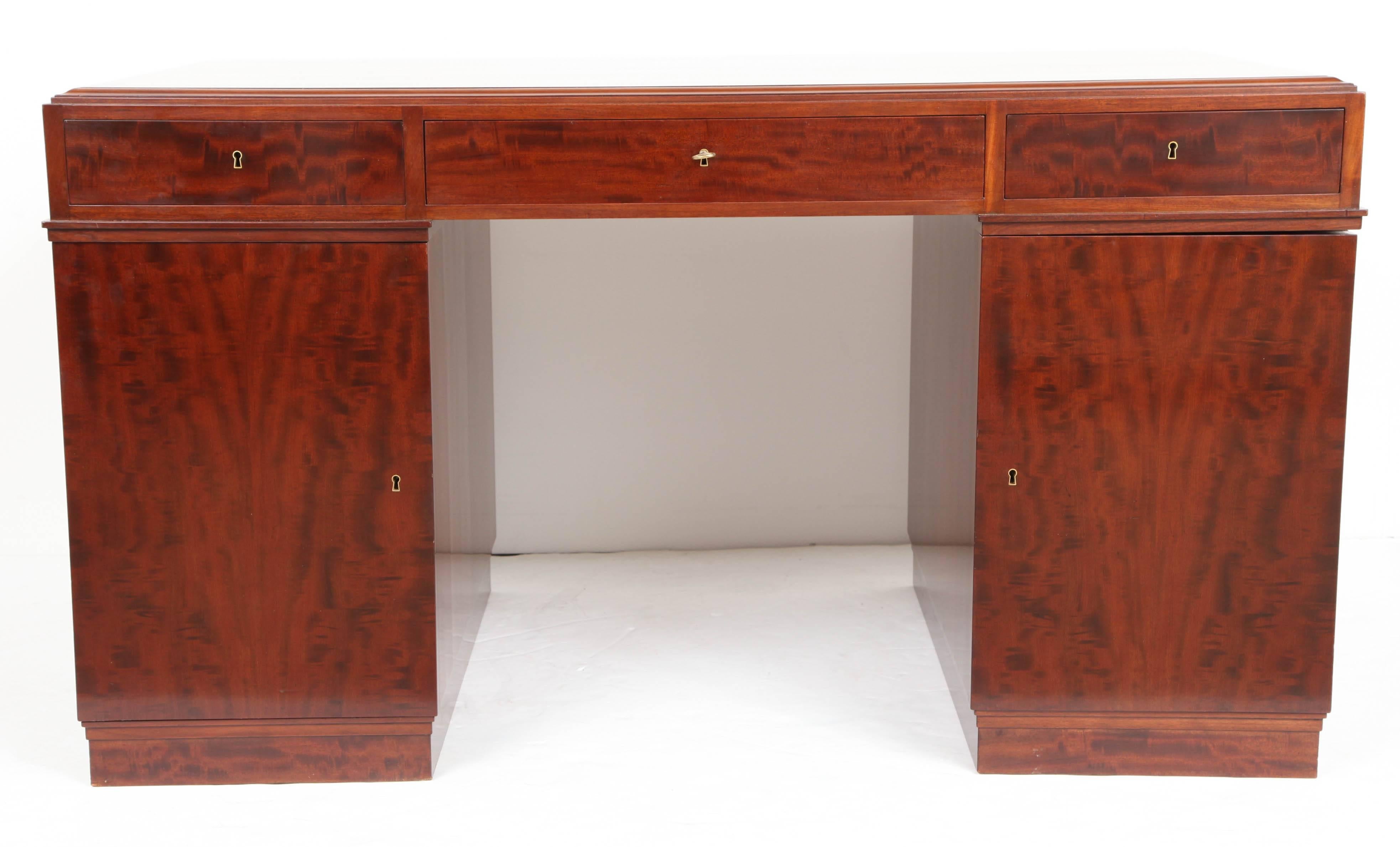 A Danish well-figured mahogany pedestal desk by Frits Henningsen, Circa 1930-40, the rectangular top with ovolo profile edge above a frieze with three drawers, flanked by pedestals, one with shelves, one with drawers, raised on a plinth base. 