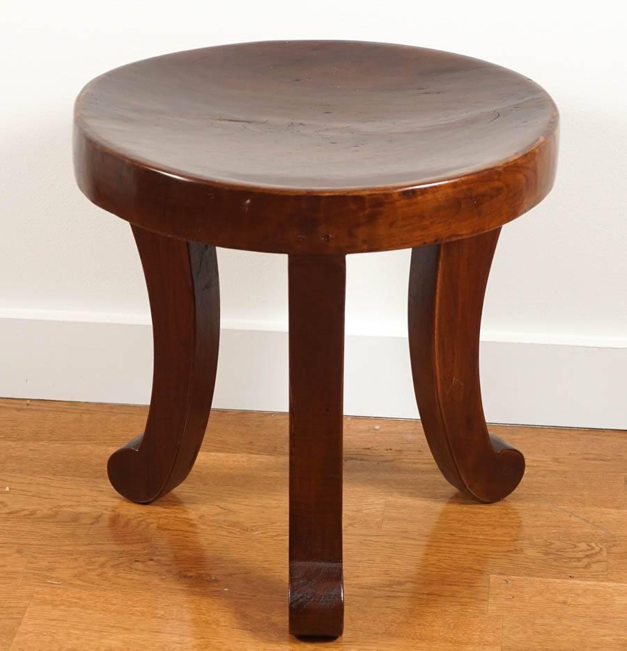 charming, solid teak stool, perched on three legs.