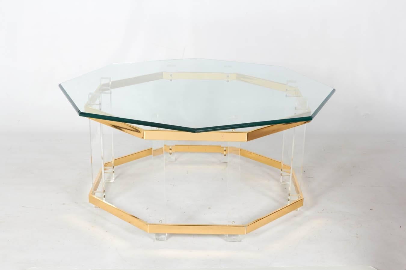 Octagonal coffee table with a beveled glass top over Lucite supports and brass trim. This version shows the glass shifted so that the points of the glass top are positioned over the middle of each panel below. Please contact for location. 