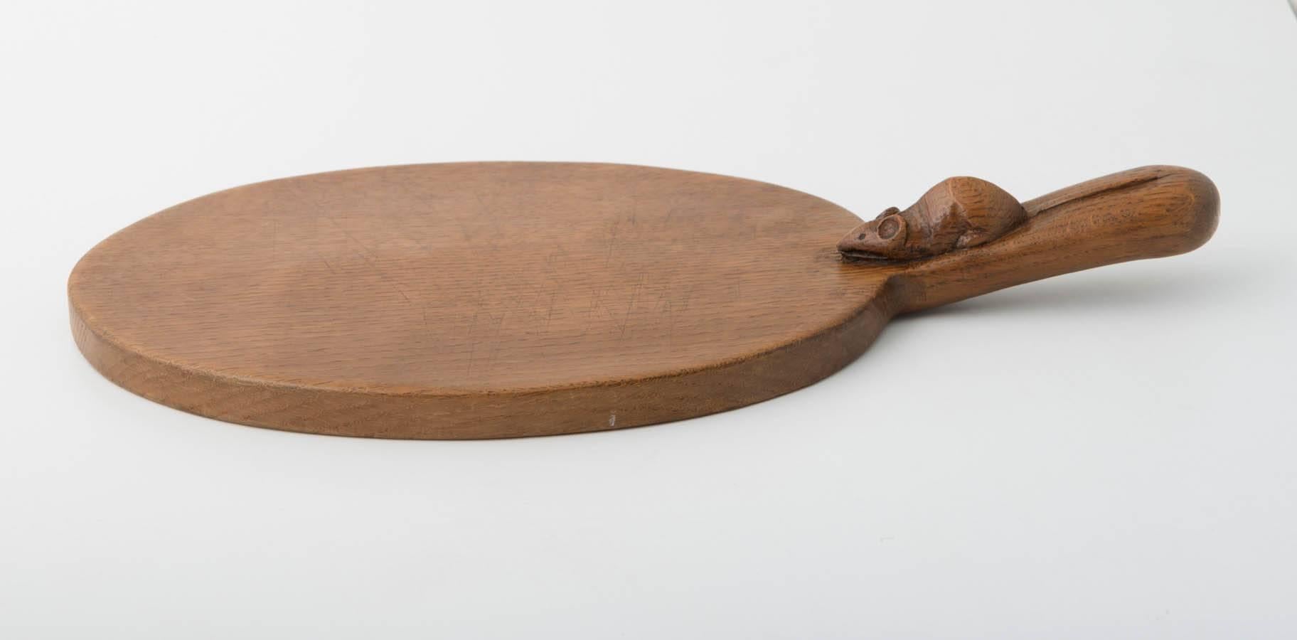 A Robert Mouseman Thompson cheese board.
Carved mouse to handle.
Slightly adzed,
English, circa 1970
Measures: 38.5 cm across.
 
