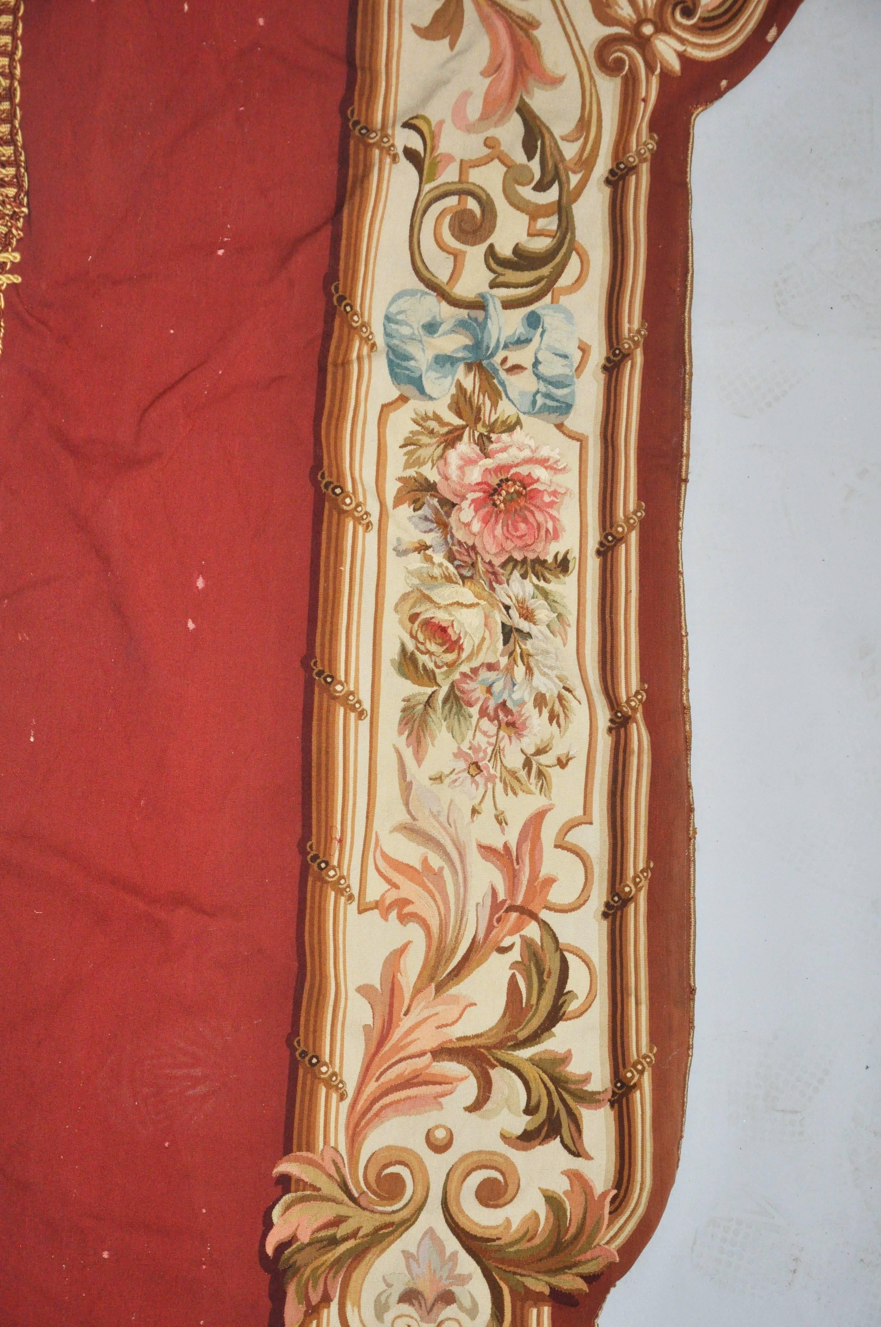 19th Century French Palatial Savonnière Needlepoint Wall Hanging. Portico (door opening) shaped opening, red silk background with shapely opening with creamy field with trailing pink and white floral, gold scrolling and design, blue ribbons, silk