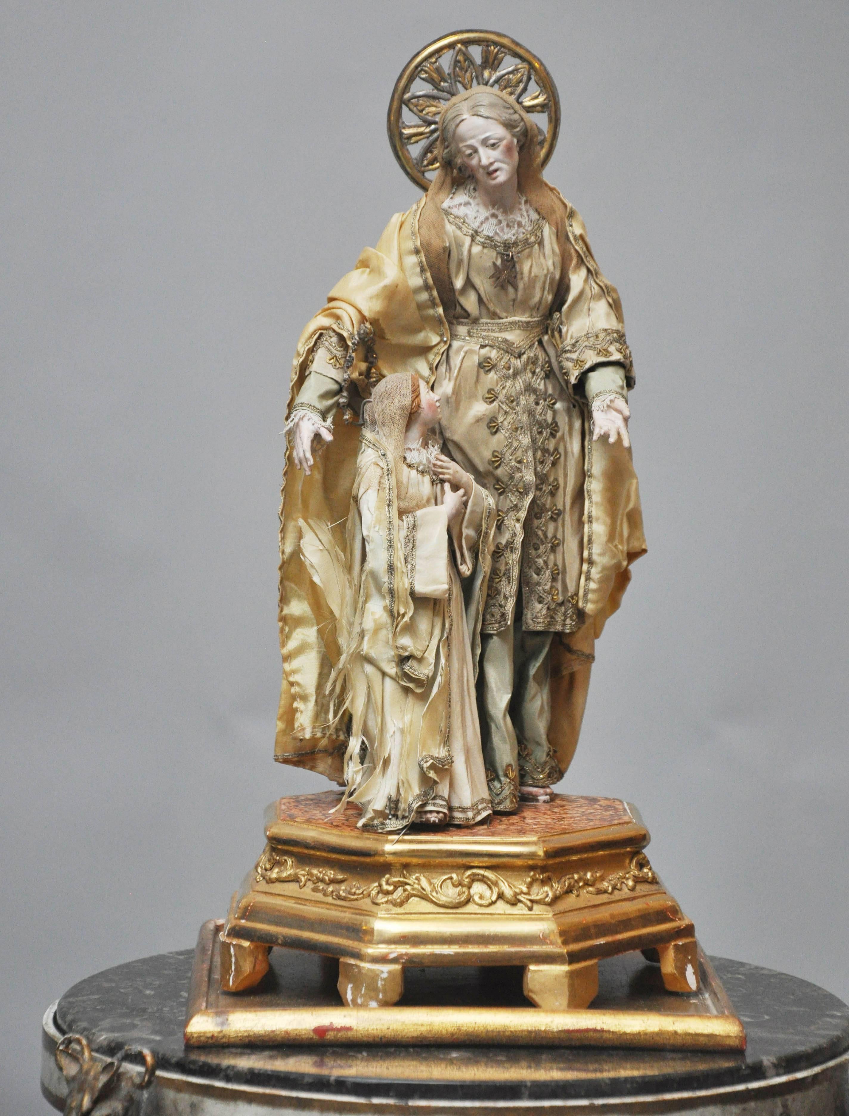 18th Century carved gesso statue depicting  St. Anne with young Mary, the little girl who would grow up to become the mother of Jesus.  Intricately carved figures draped with silk garments, supported on a shapely gilt octagon pedestal  resting on a