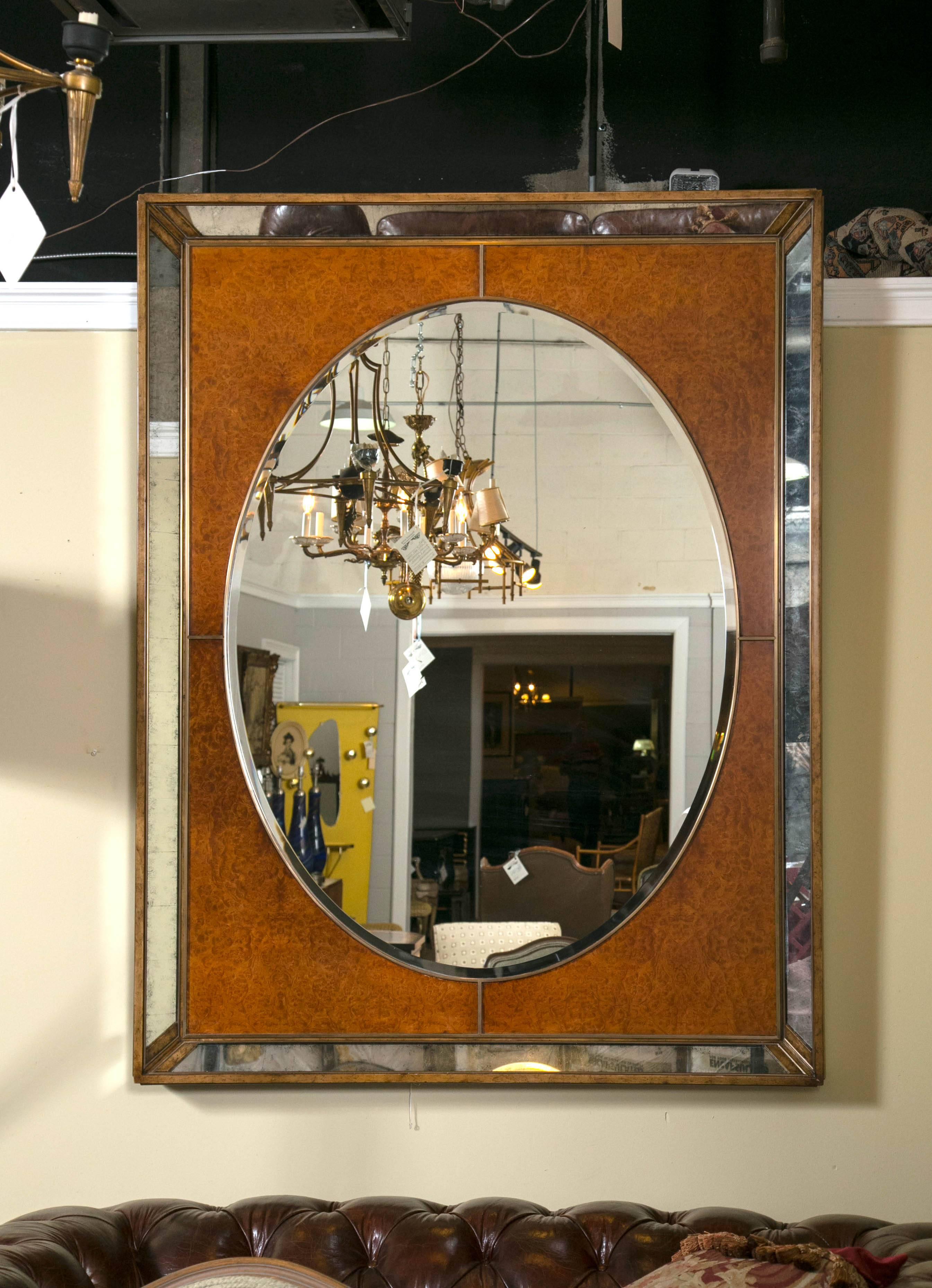Monumental burl and glass Art Deco mirror stamped Theodore Alexander. A burl frame encasing antiqued mirrored borders on the outset and gilt and burl encasing the inset beveled mirror. A Mid-Century Modern statement. This piece is fabulous. A grand