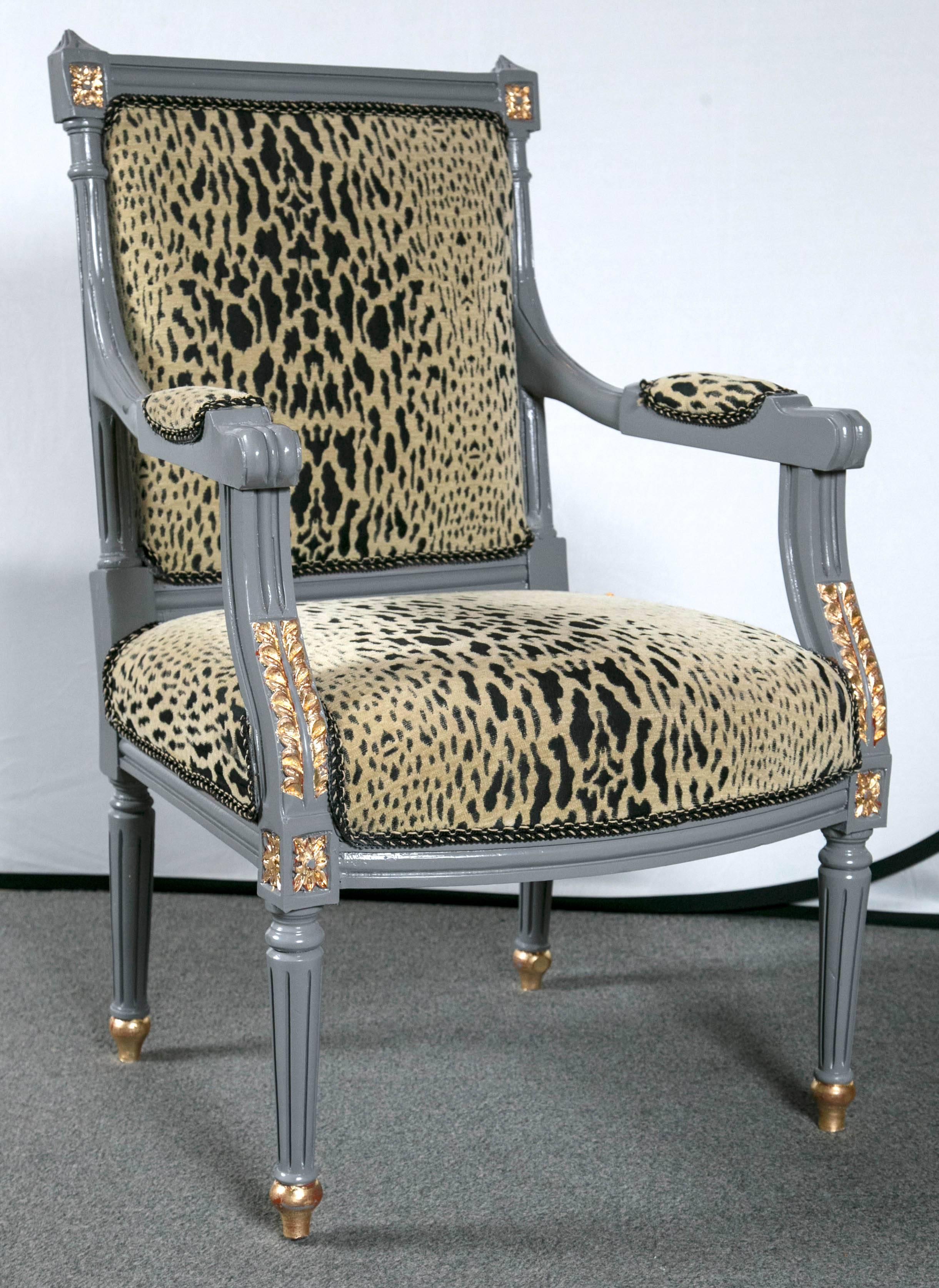 Pair of Louis XVI style fauteuils. The leopard print is cozy and stately. Steel gray and gilt gold style. Jansen. Steel gray painted with bronze sabots and decorative flower motifs. The subtle claw arm has fabric on the armrest. A pretty pair.
