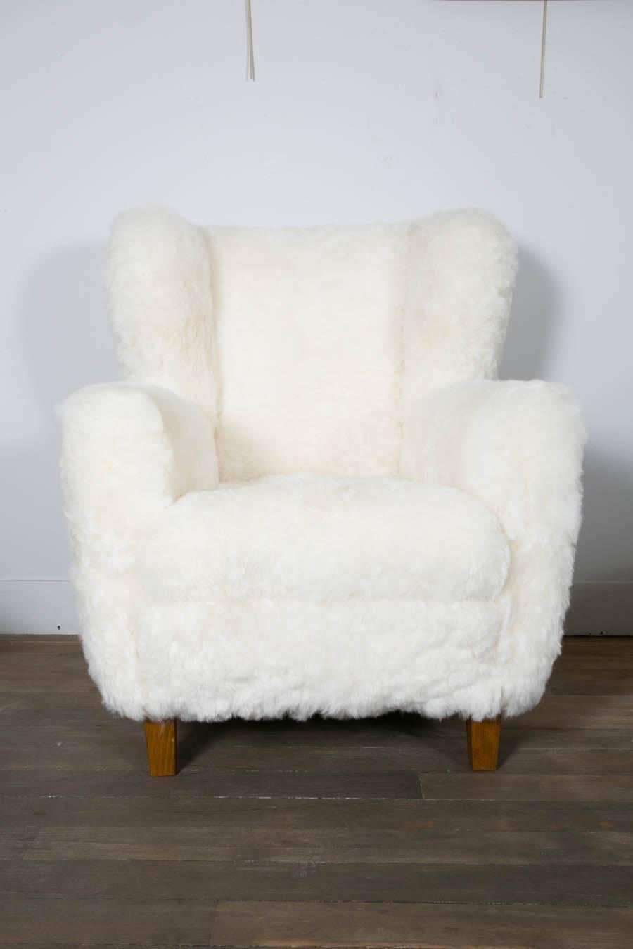 A pair of Wingback lounge chairs, newly re-upholstered with sheepskin. 
Scandinavian modern, circa 1960.
