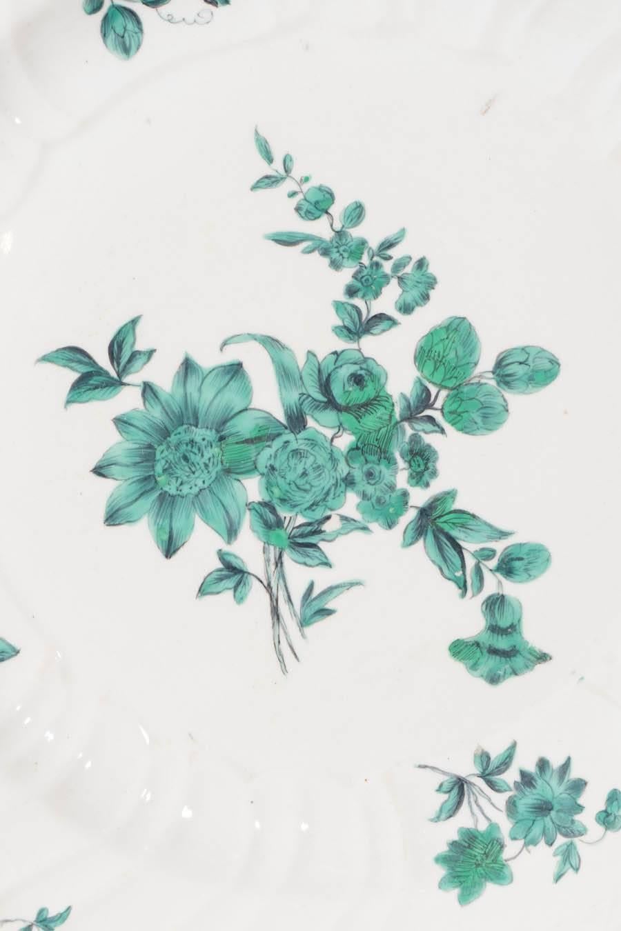 Each dish is decorated with unique hand-painted bouquets of flowers painted in a deep green. The borders are impressed with a subtle basket weave design. The gilded edges are softly lobed. The overall effect is lovely, very much in the style of