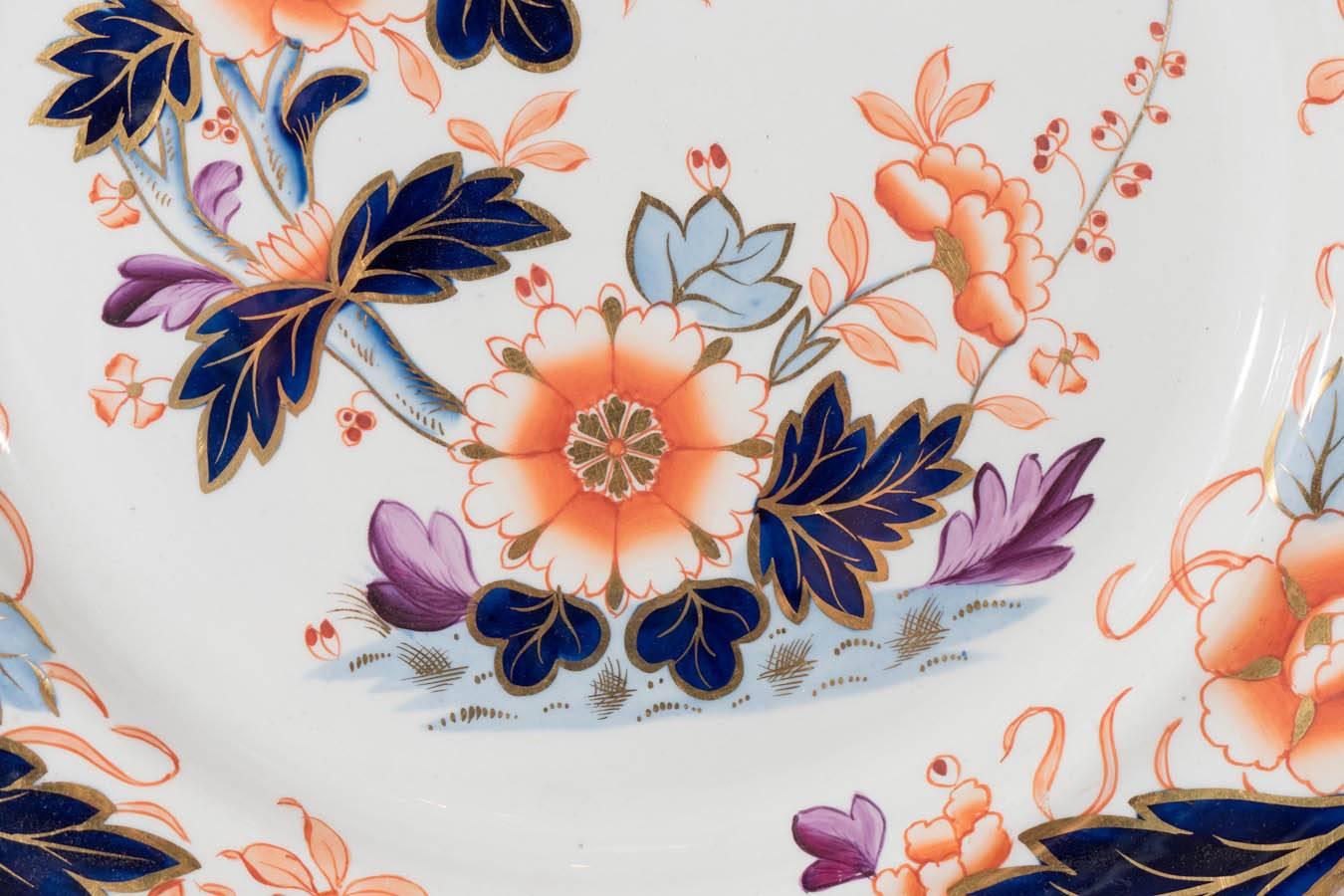 A set of dessert or salad dishes in the Imari style painted with the traditional orange, gilt and cobalt blue, but softened here with pale blue and lilac. The colors combine in a lovely asymmetrical floral setting. The border beautifully gilded. In