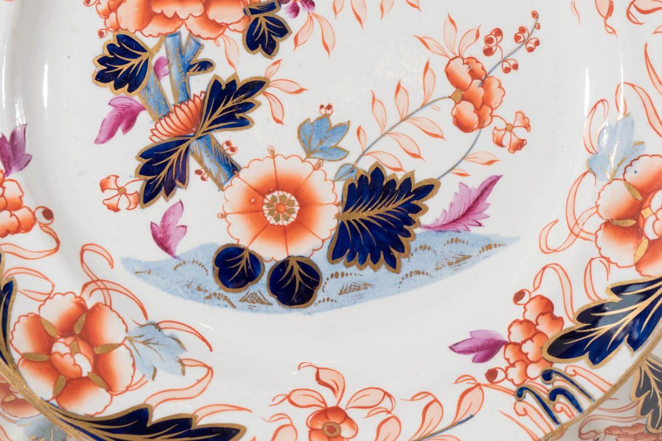A set of dishes in the Imari style painted with the traditional orange, gilt and cobalt blue, but softened here with pale blue and lilac. The colors combine in a lovely asymmetrical floral setting. The border beautifully gilded. In this pattern we