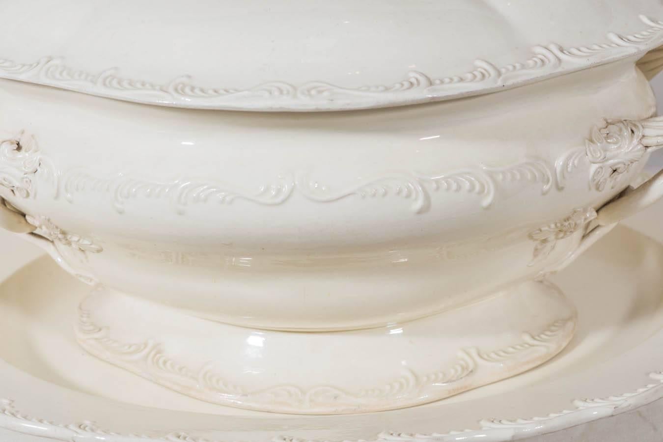 An exceptional 18th century creamware soup tureen and stand perfectly proportioned. Beautifully decorated with an outstanding pomegranate finial, intertwined rope handles, and crisply molded feather edge border, this tureen is one of the finest we