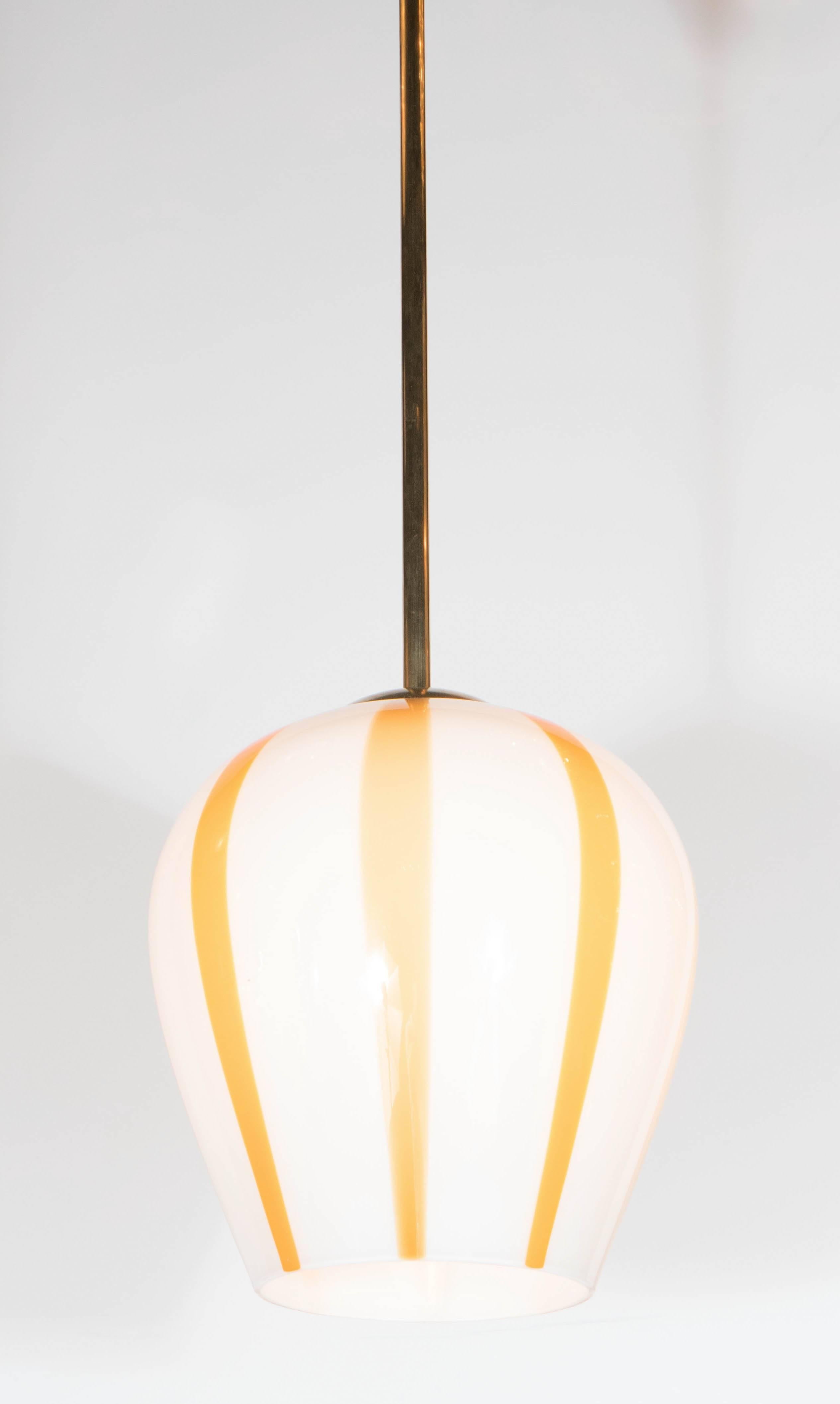 A beautiful Mid-Century Modernist pendant featuring a hand blown murano glass dome which is accentuated with vertical citrus-hued stripes. It also features a solid brass rod and canopy.A bright addition to any room or decor. The height on this piece