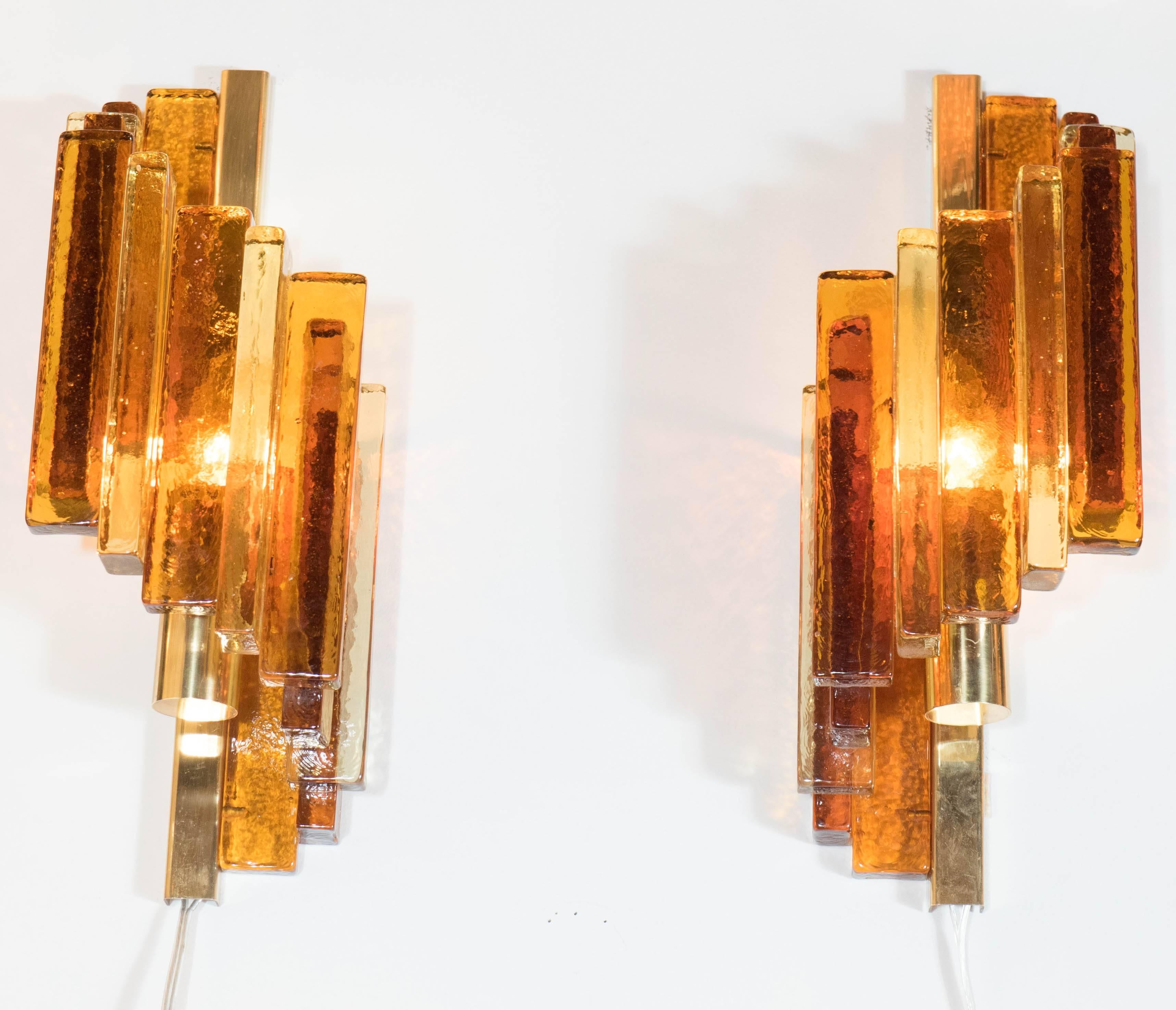 This sculptural pair of Mid-Century Modernist sconces by Hassel Teudt consist of numerous handblown amber and gold glass rods in a spiral configuration surrounding the polished brass fittings and bulb. With the light diffusing through the glass rods